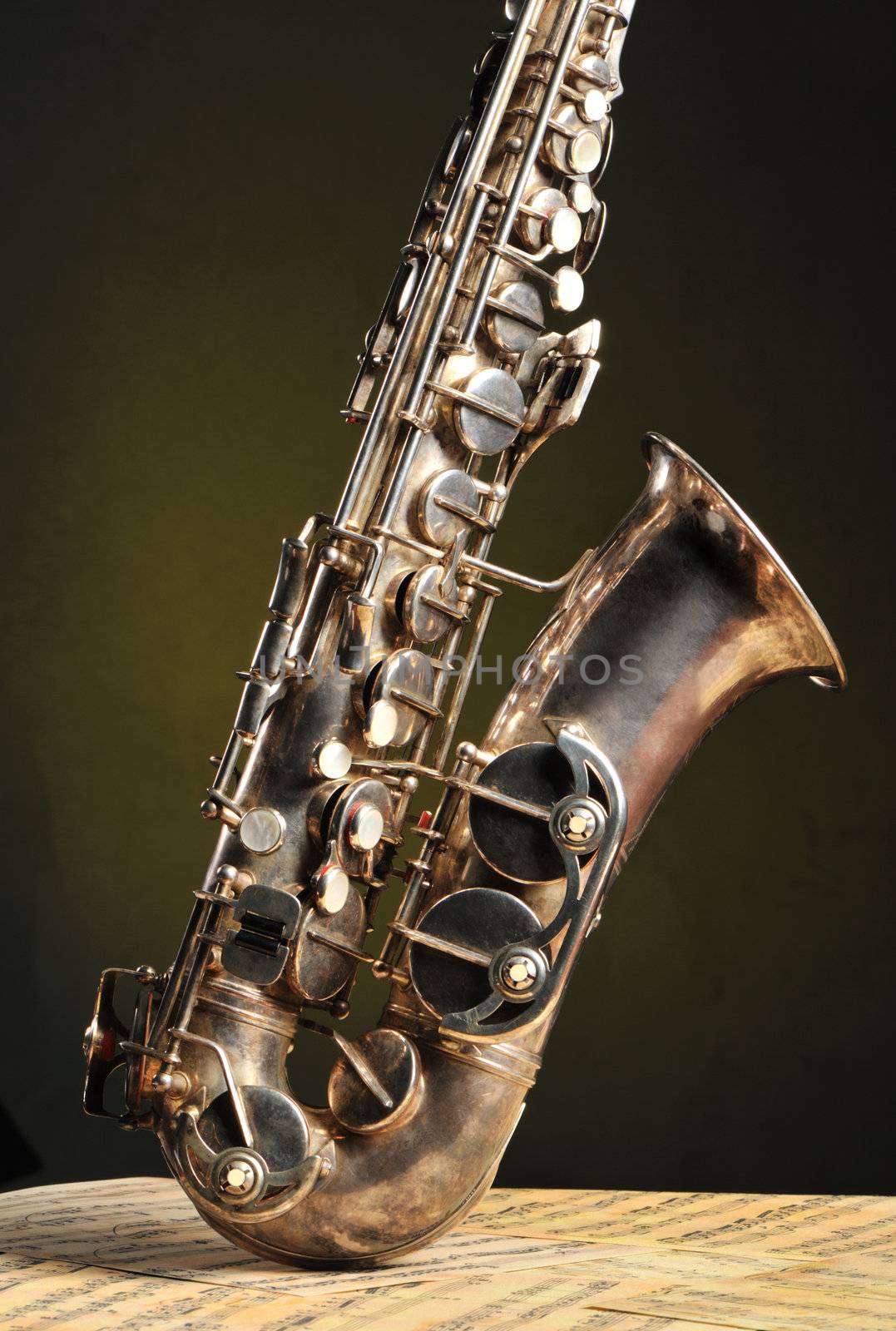 Old saxophone and notes. The Musical instrument standing on notes with classical music of the beginning of 17 centuries
