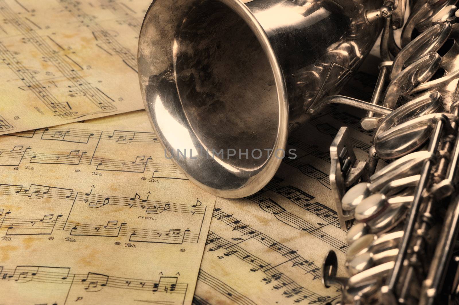 Old saxophone and notes. The Musical instrument laying on notes with classical music of the beginning of 17 centuries