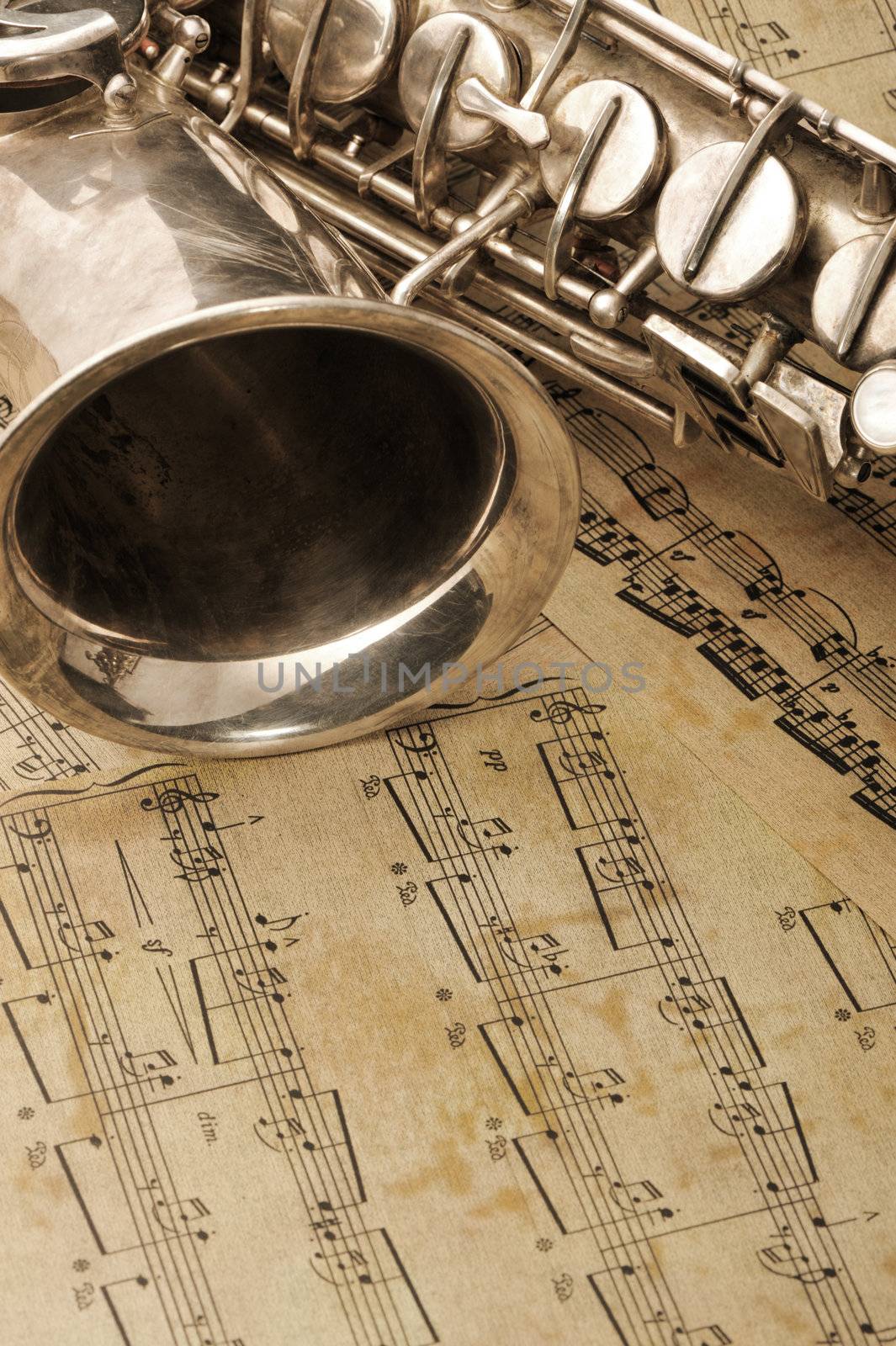 Old saxophone and notes. The Musical instrument laying on notes with classical music of the beginning of 17 centuries