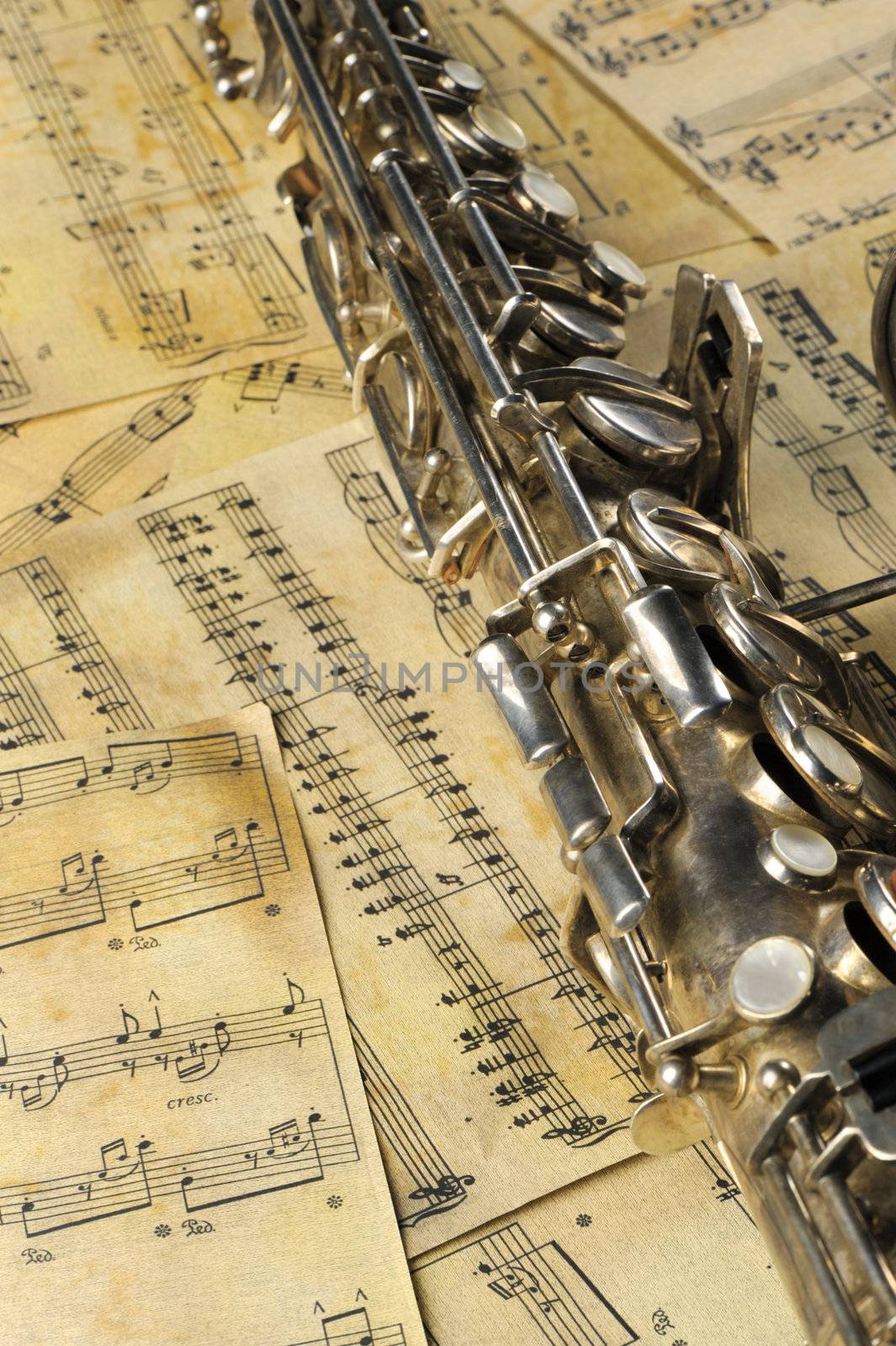 Old saxophone and notes. The Musical instrument laying on notes with classical music of the beginning of 17 centuries