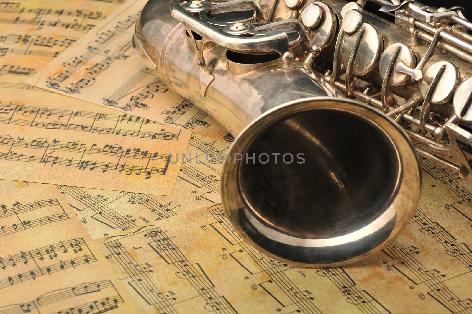 Old saxophone and notes. The Musical instrument laying on notes with classical music of the beginning of 17 centuries