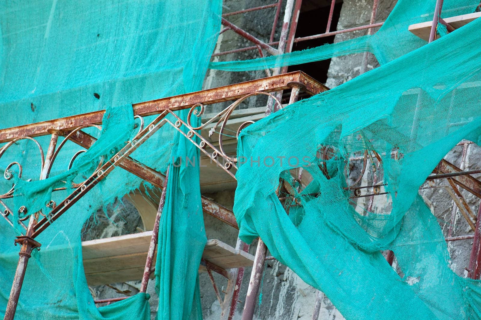 Abandoned mansion renovation. Vintage rusty metal shed and torn scaffold debris netting.