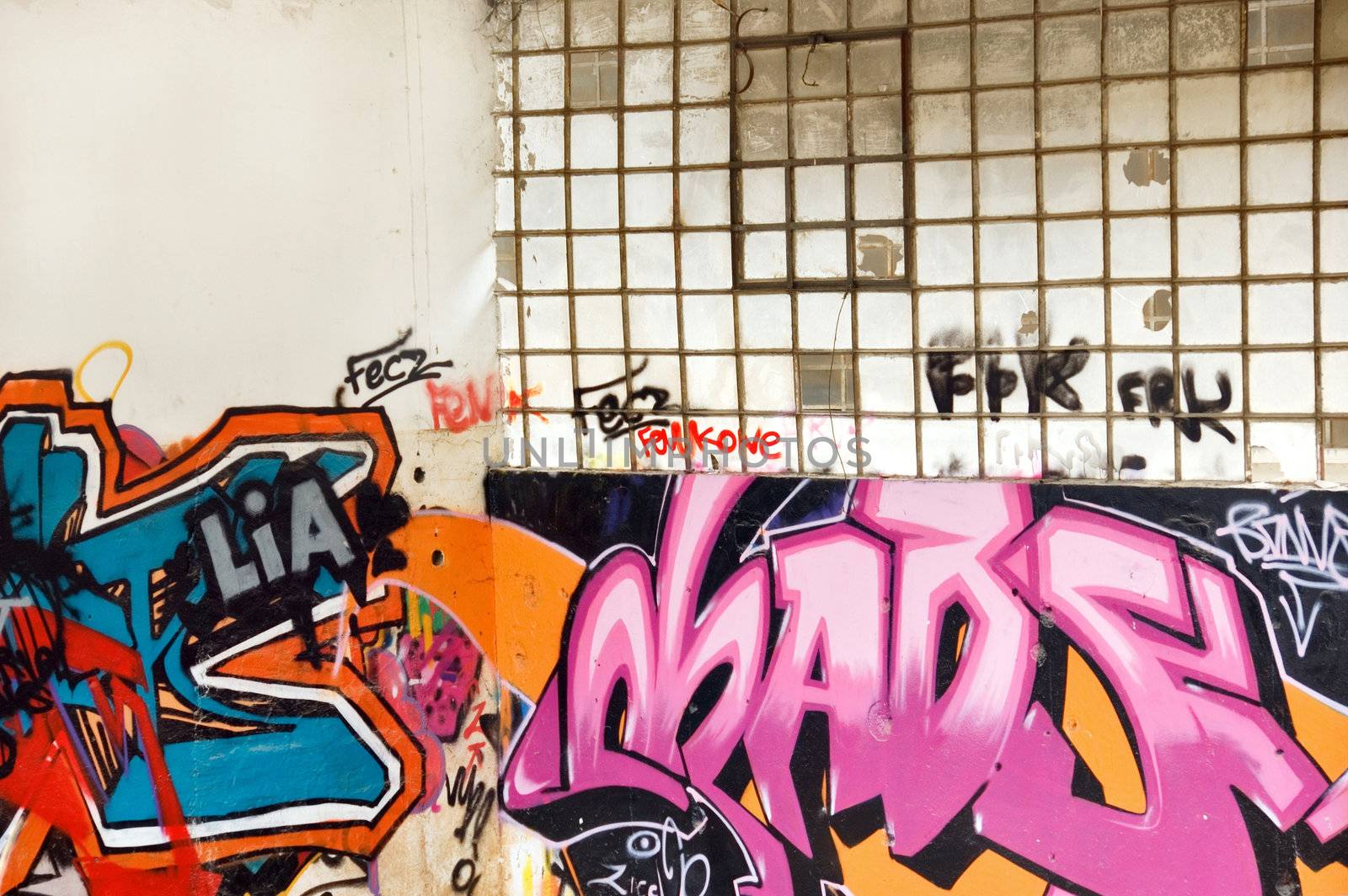Graffiti covered wall and broken windows inside a partially demolished factory.