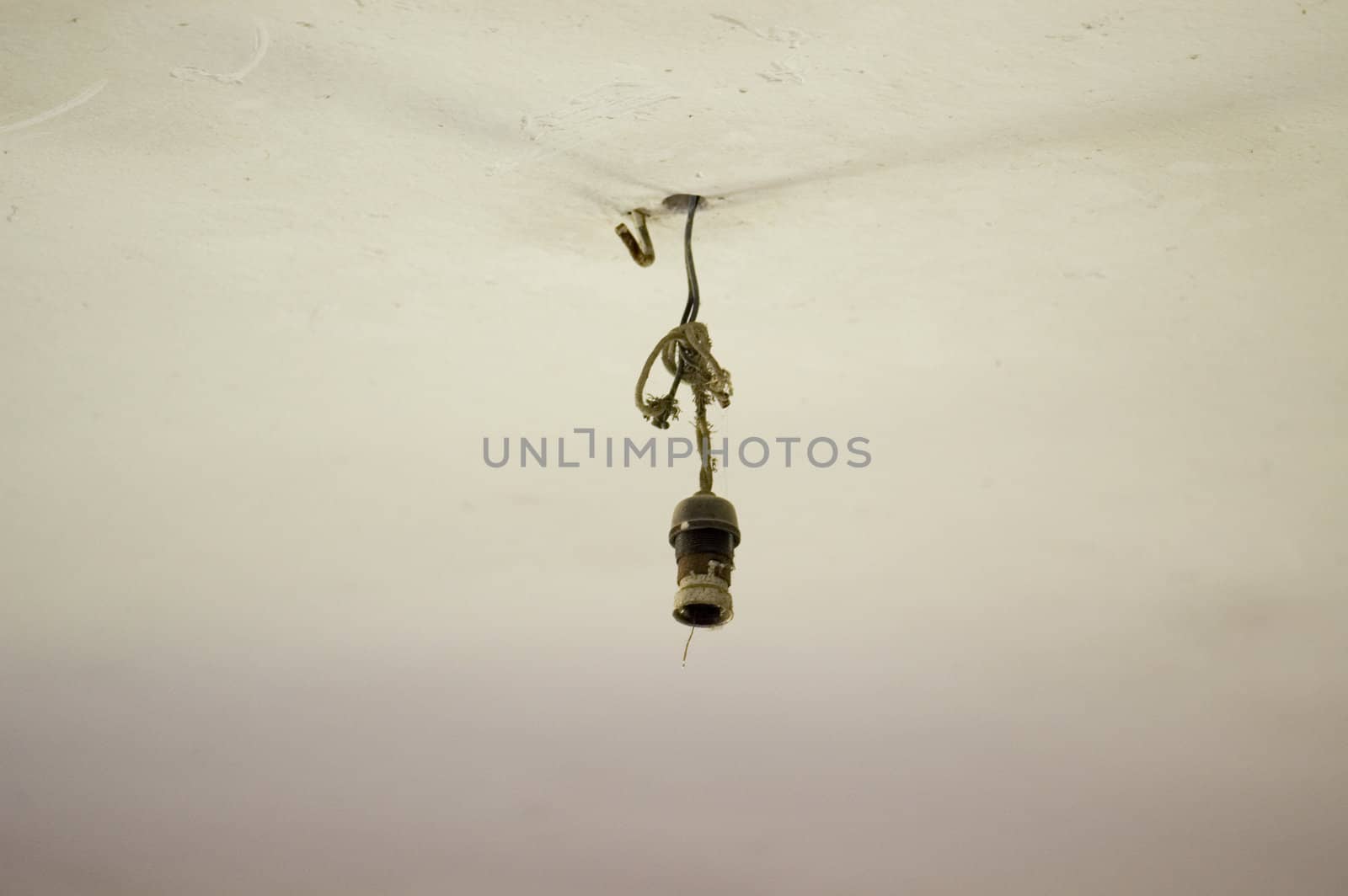 Broken light bulb electrical wiring and ceiling detail inside an abandoned house.
