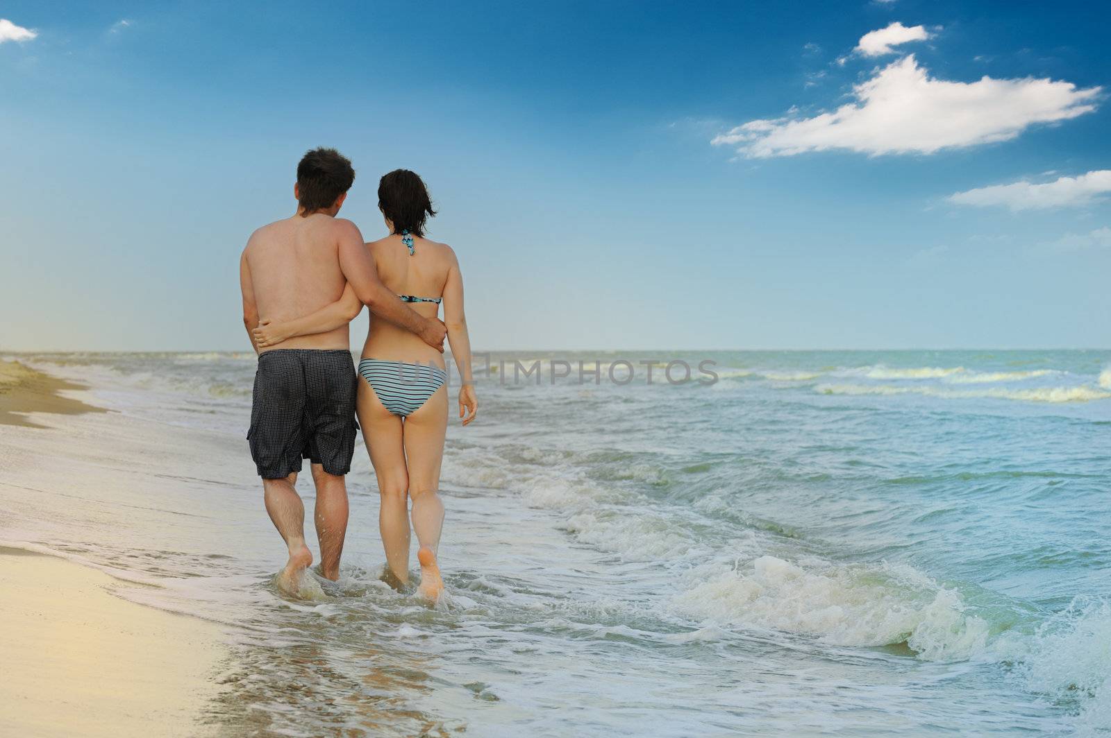 Pair on seacoast. The enamoured guy and the girl walking on coast