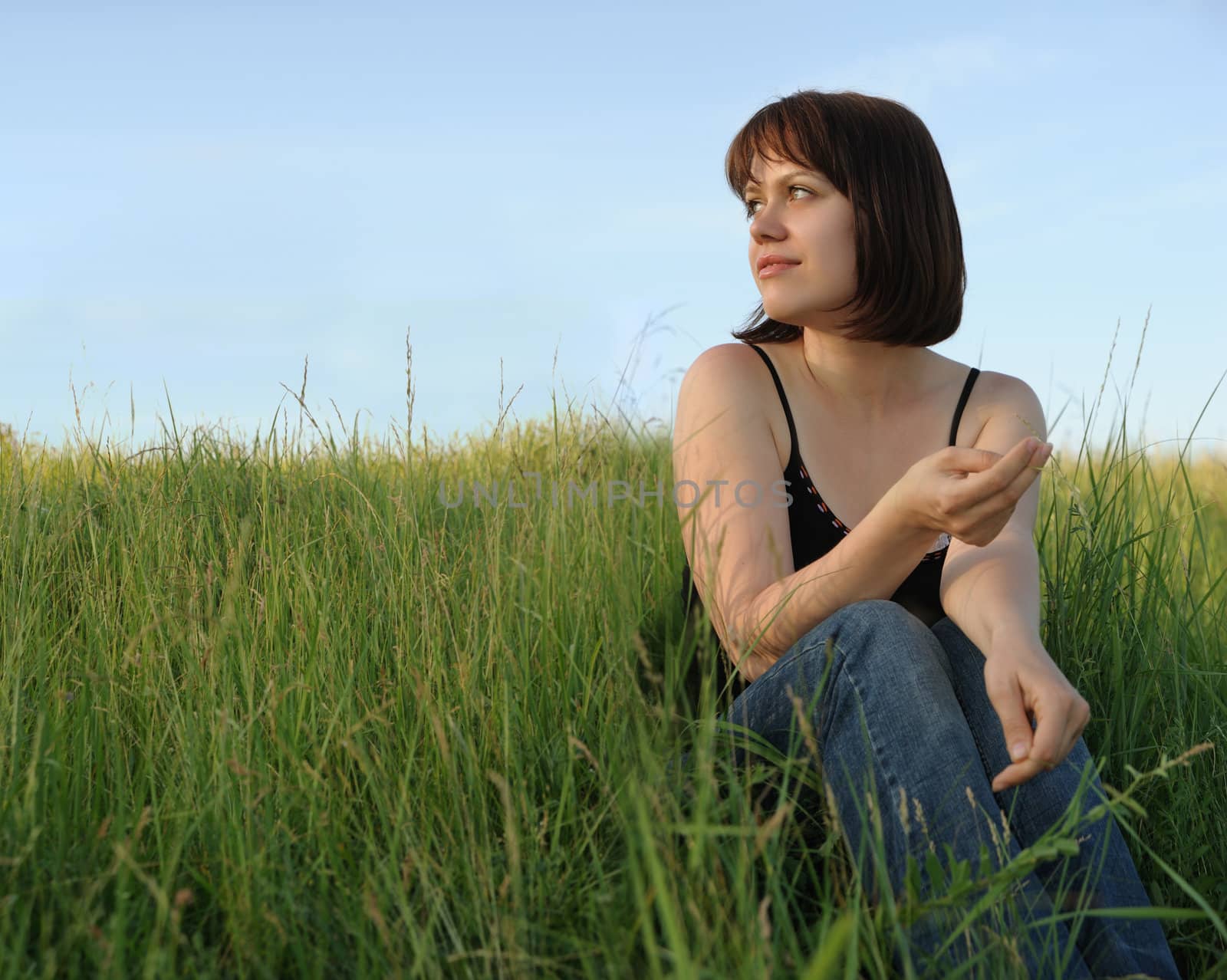 The girl on field. The young girl on green field on a background of the dark blue sky