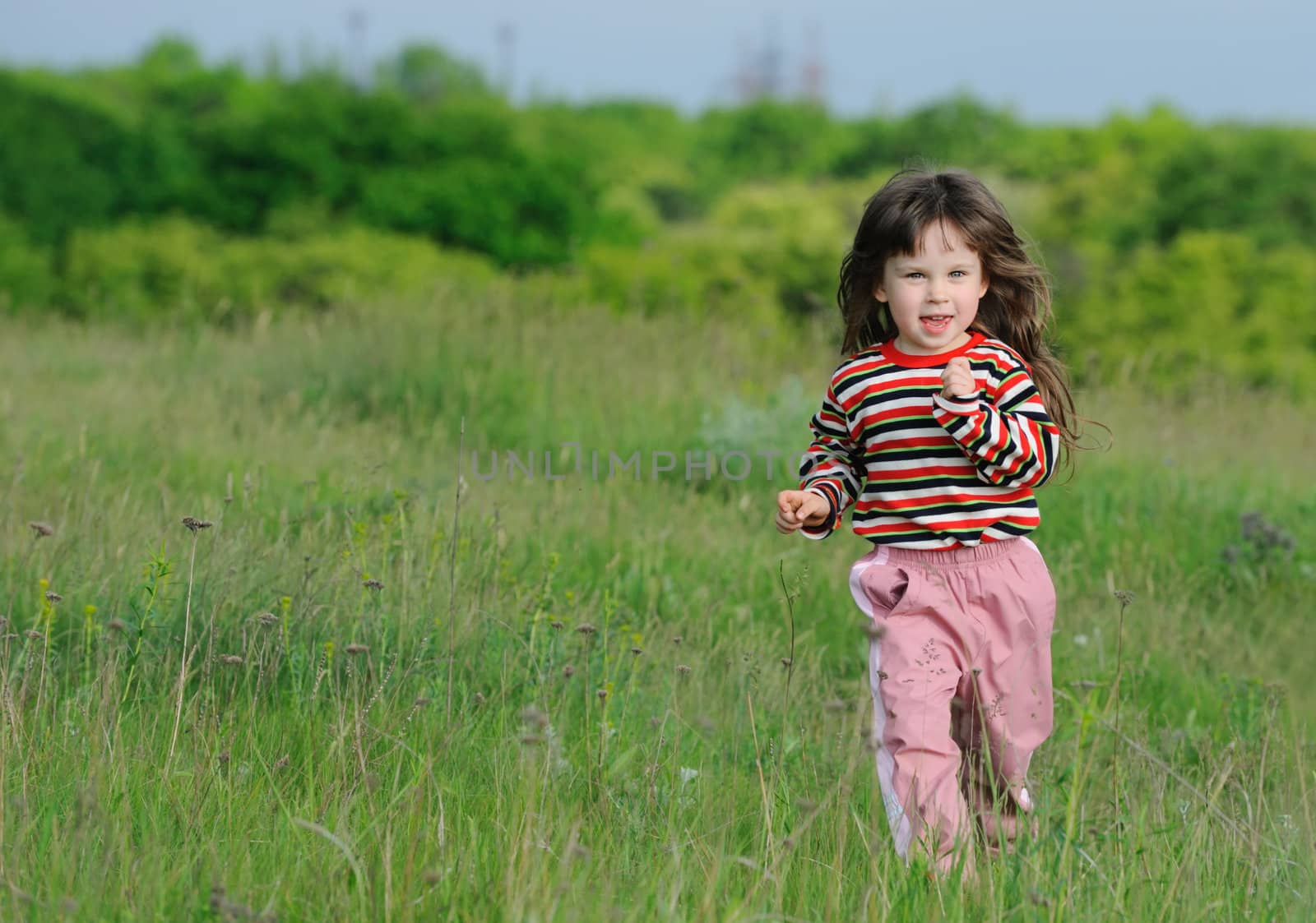 The running girl on a green floor. The happy child on a spring meadow