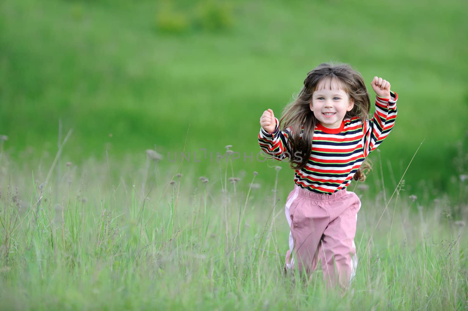 The running girl on a green floor. The happy child on a spring meadow