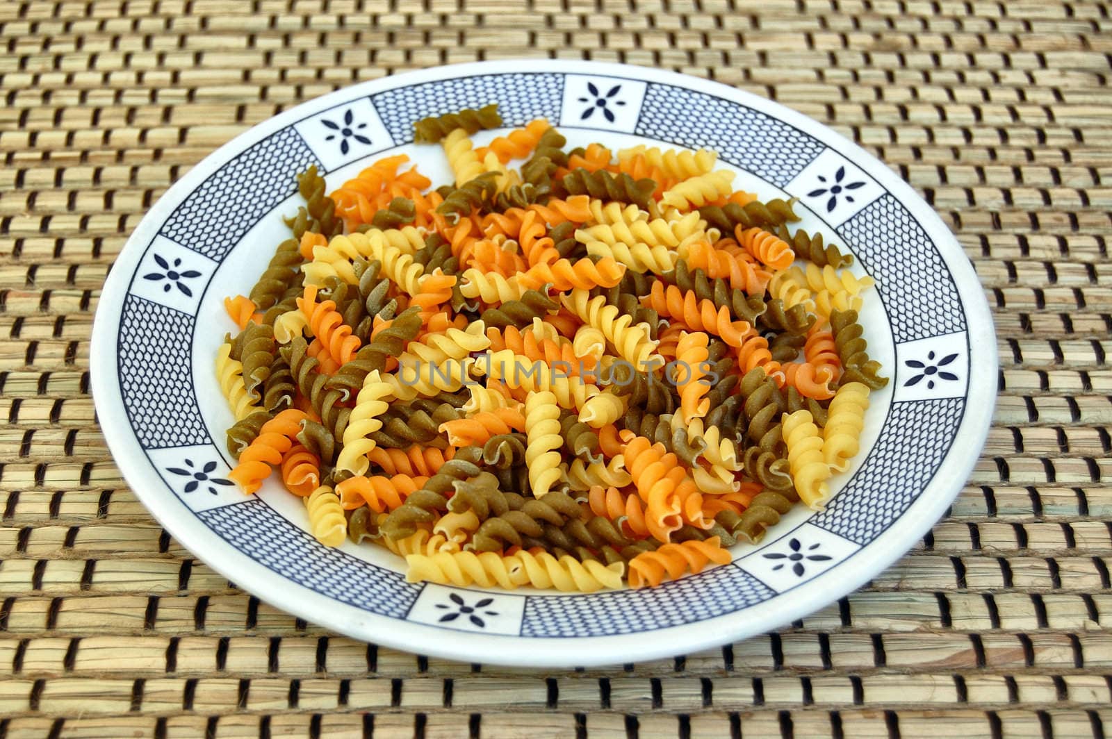 Three different flavors of raw fusilli pasta. Italian food background.