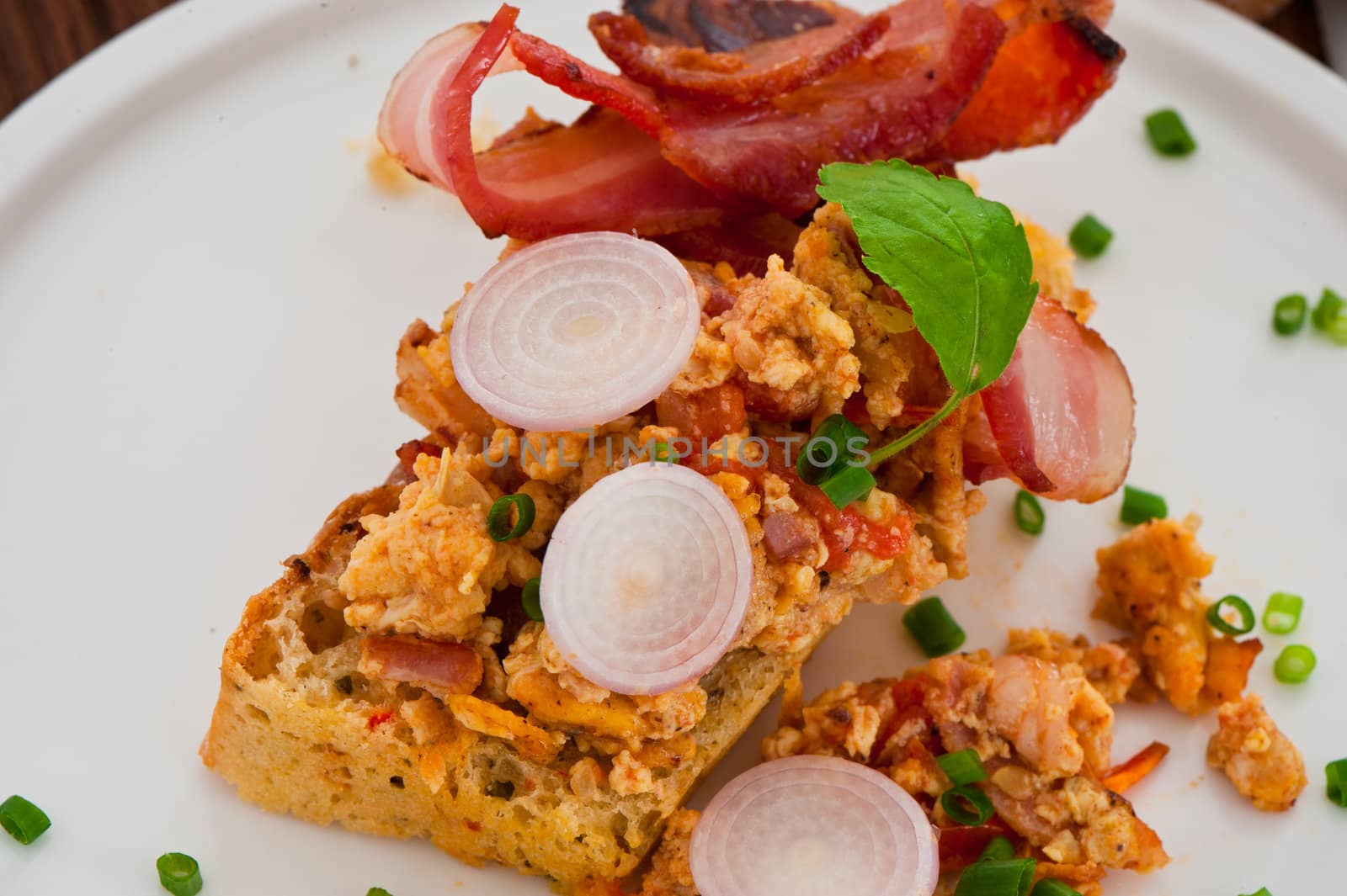 Homemade mediterranean bread with butter scrambled eggs and a leaf of basil