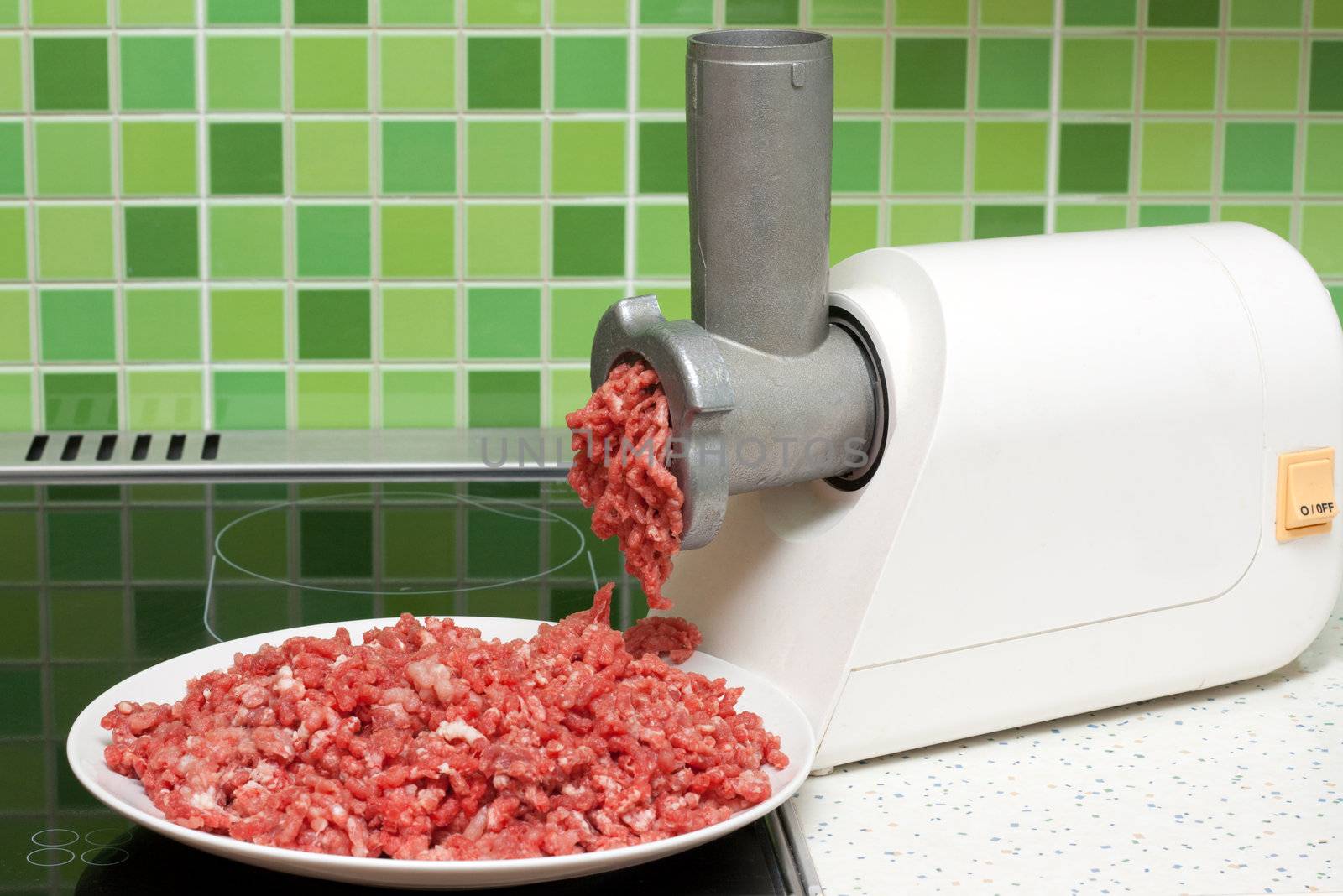 Meat grinder on kitchen, mincemeat on background of the tiled bar
