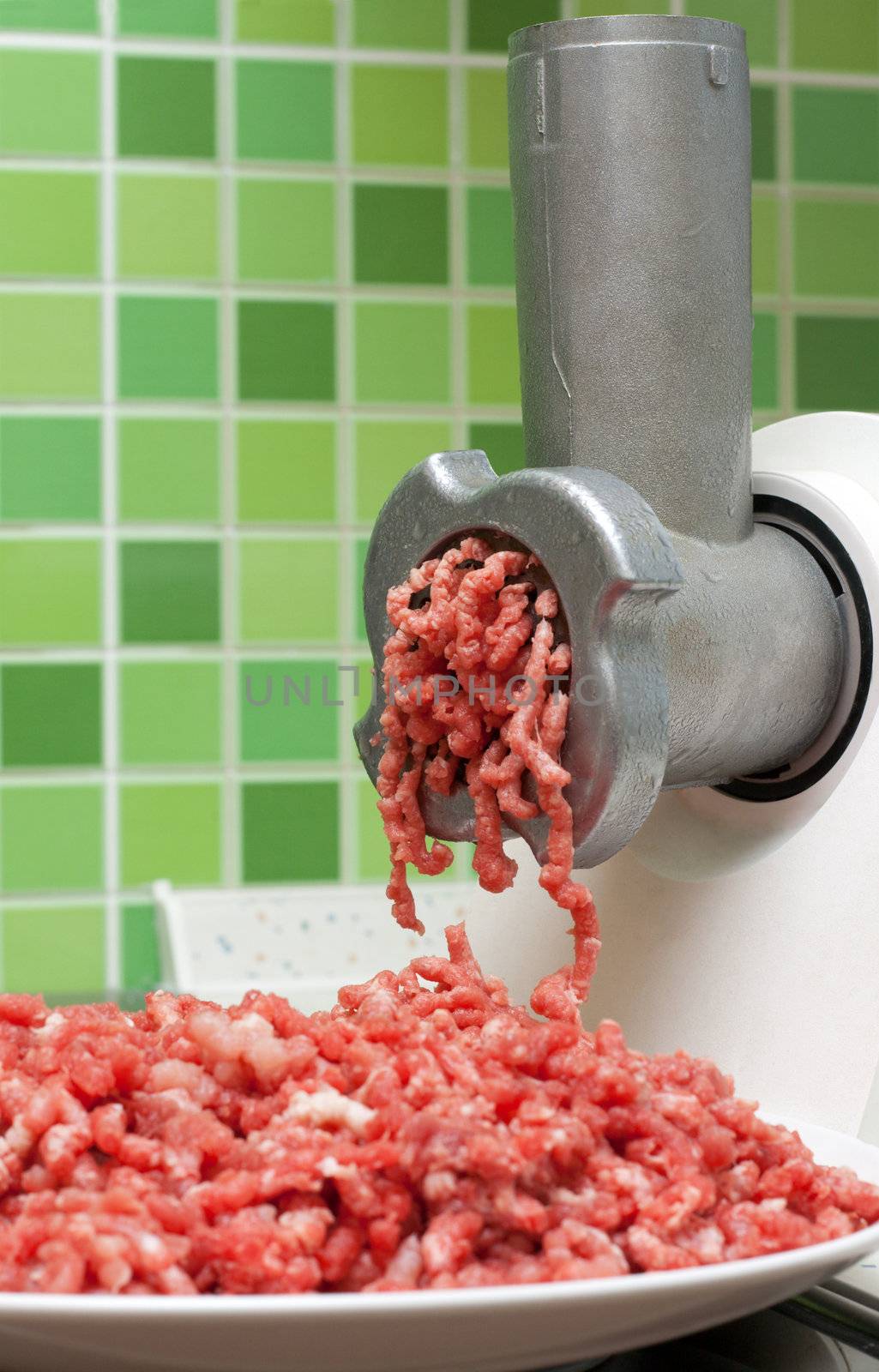Meat grinder on kitchen, mincemeat on background of the tiled bar