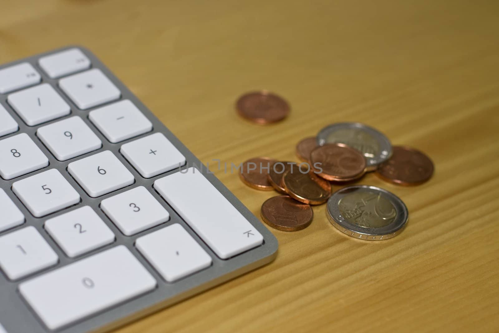 Keyboard and euro coins on wooden desk by gewoldi