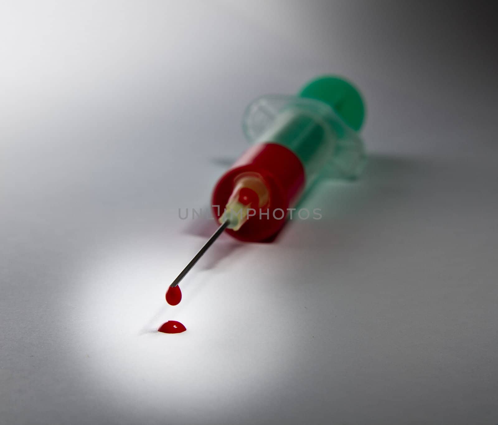 syringe laying on table filled with blood. Focus on needle