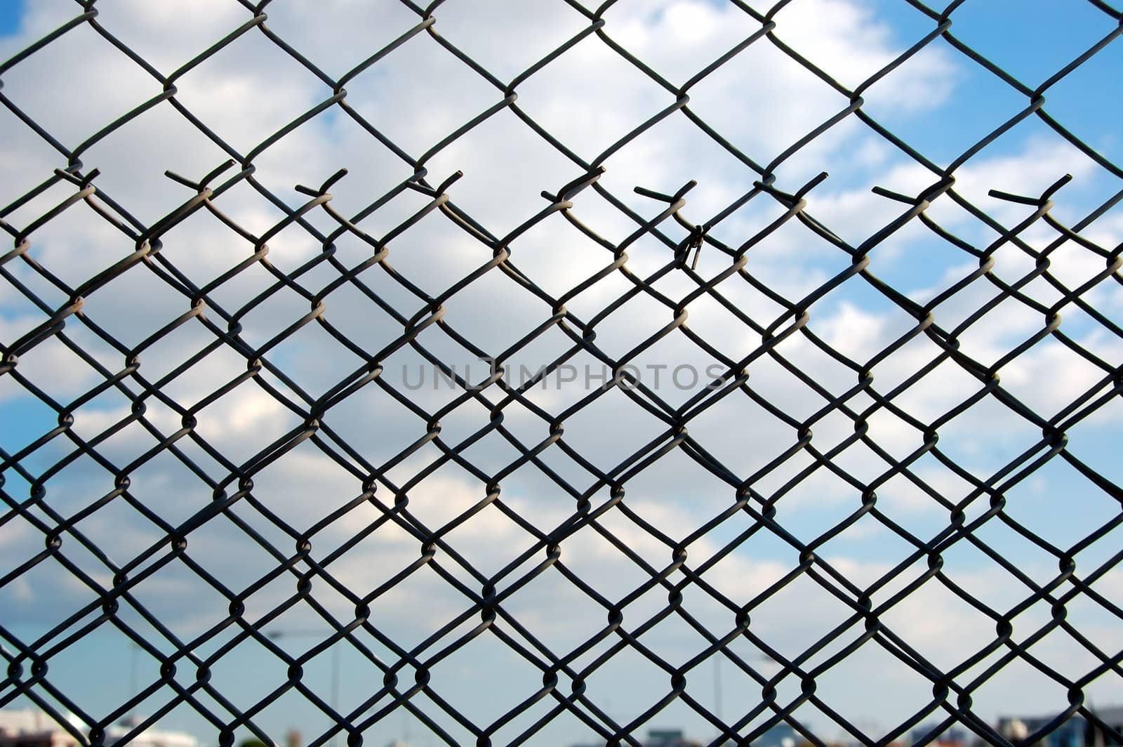 Wire mesh chain link fence pattern against blue sky.