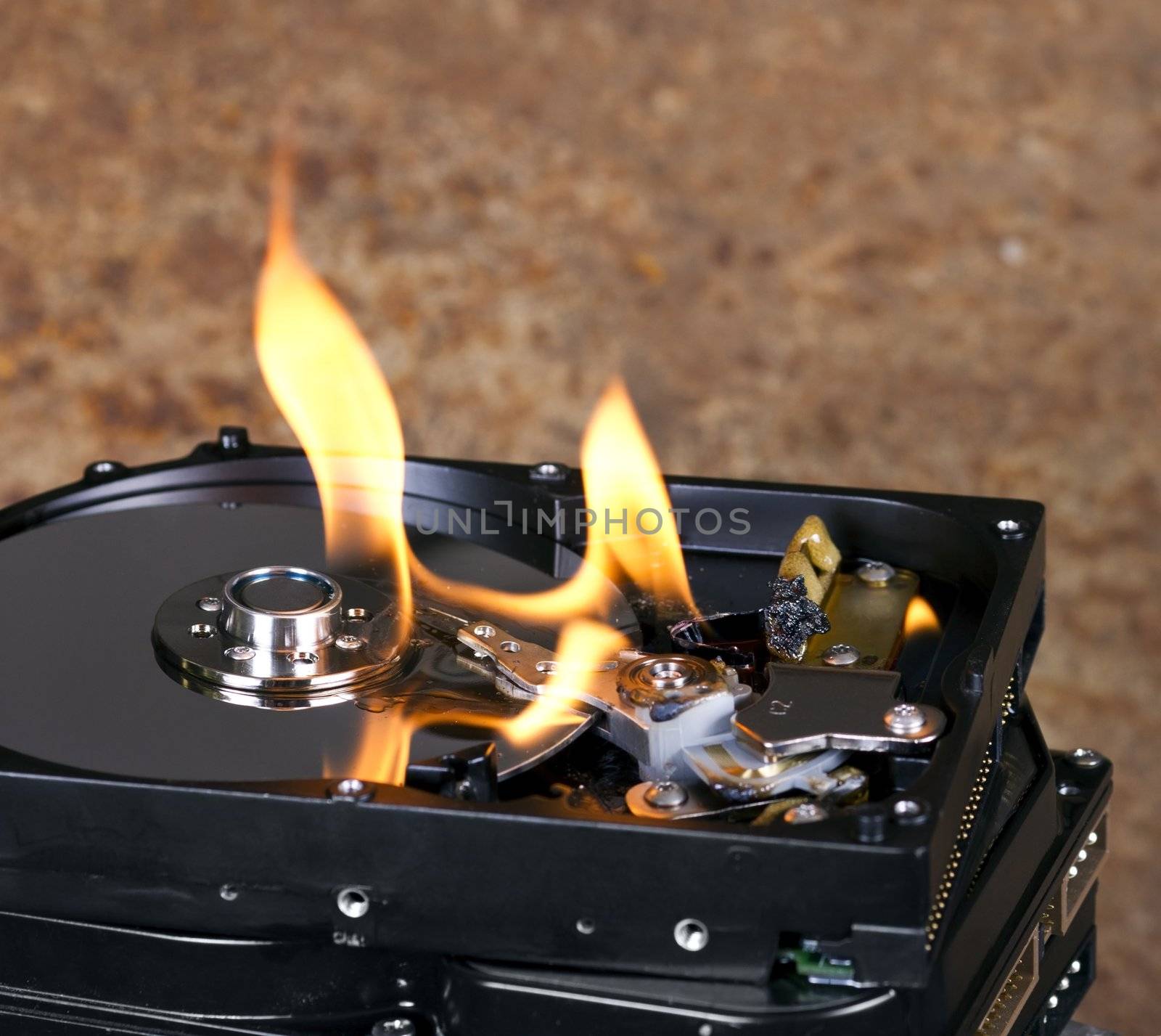 Stack of burning hard drives in close up shot. Nice flames on the drive. Rusty background