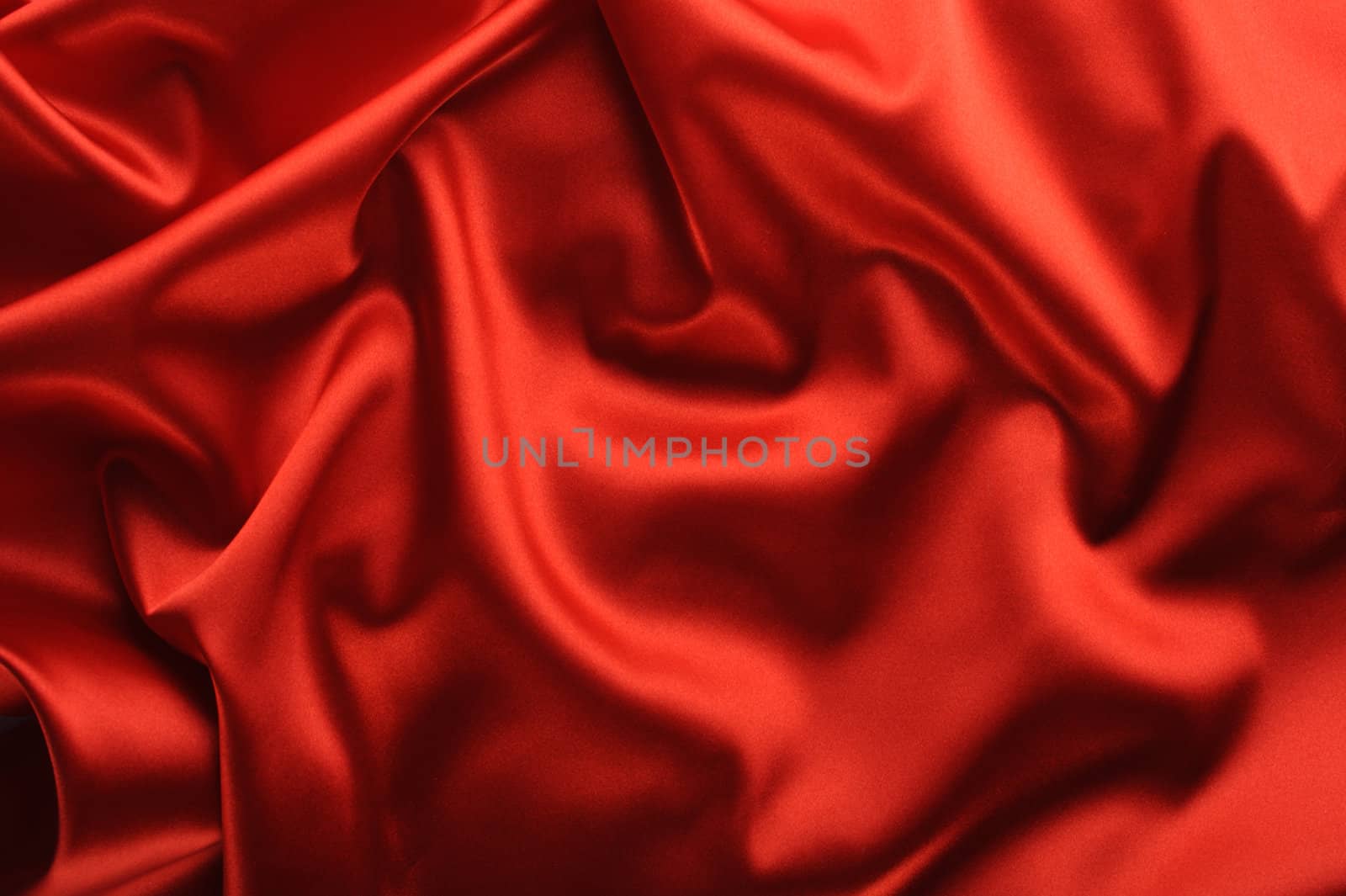 red satin background. A satiny fabric with beautiful light-shadow waves