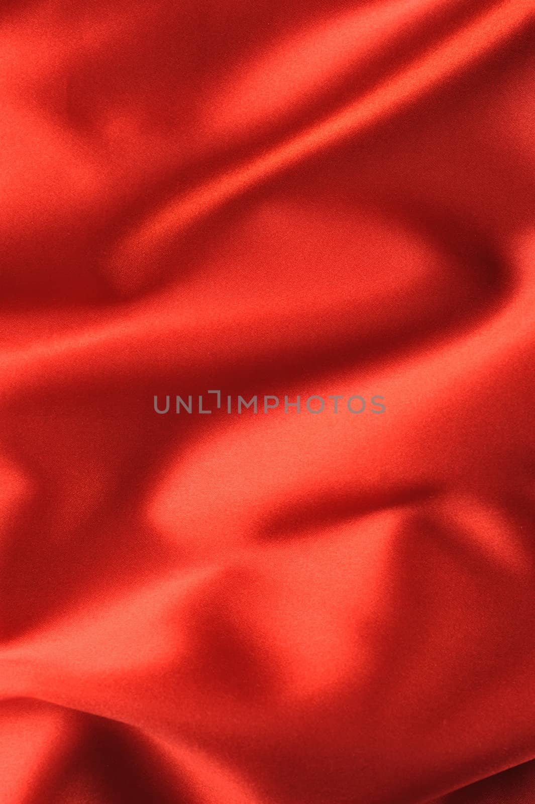 red satin background. A satiny fabric with beautiful light-shadow waves