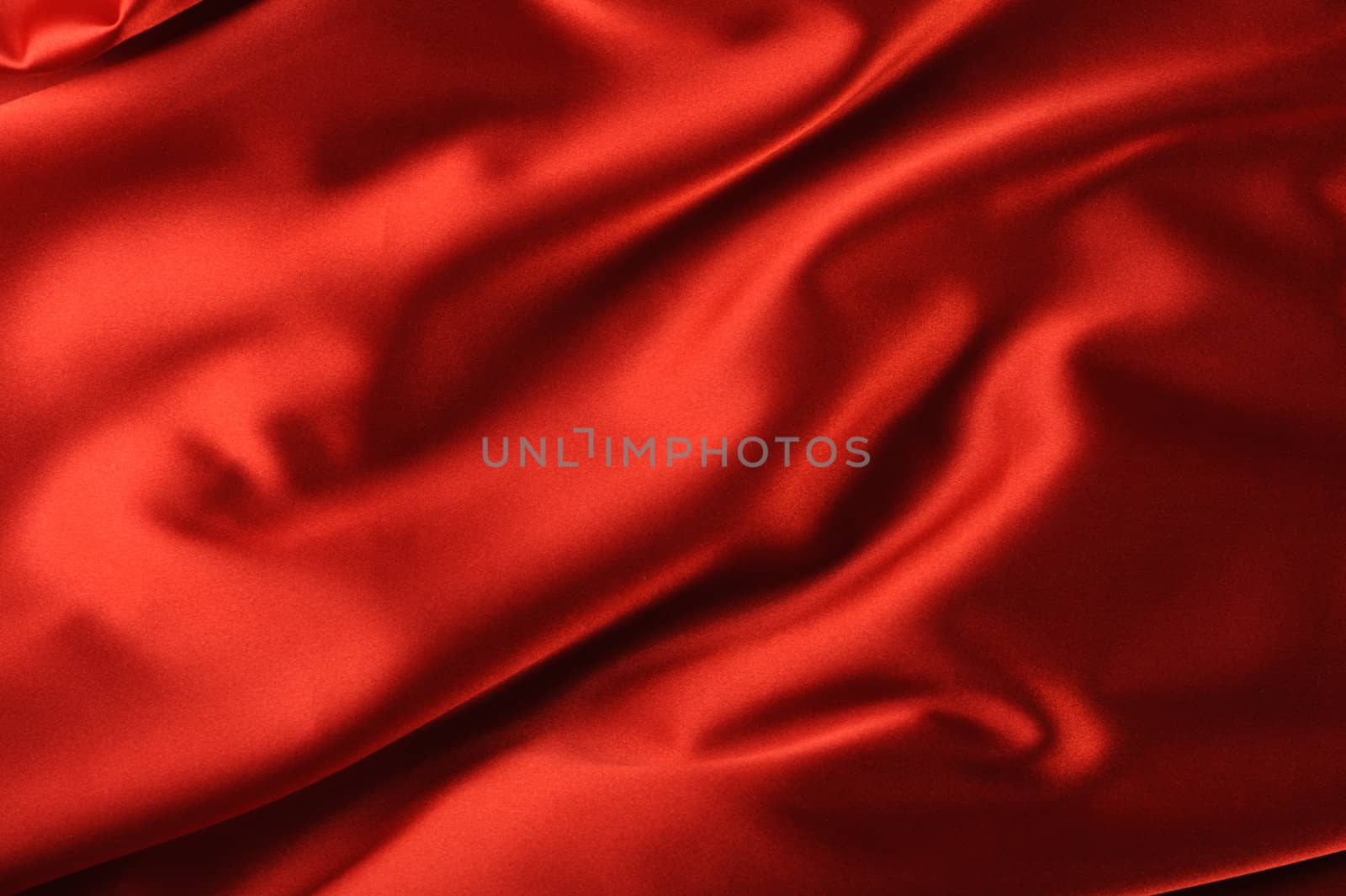 red satin background. A satiny fabric with beautiful light-shadow waves