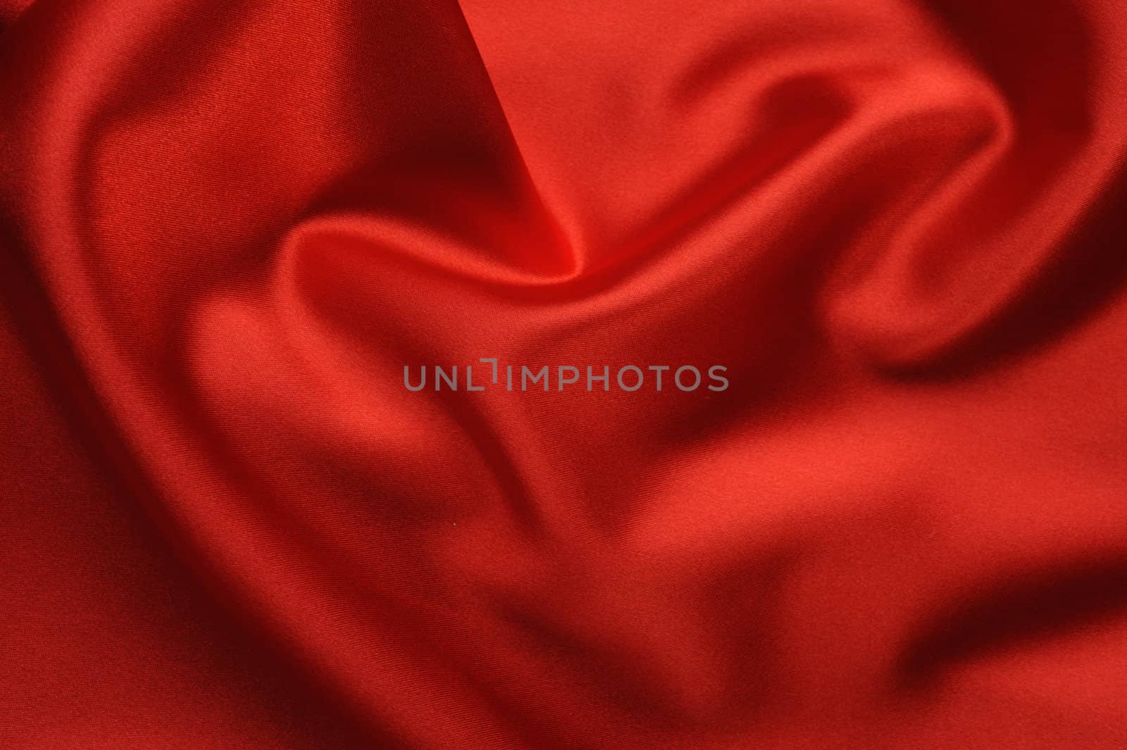 red satin background. A satiny fabric with beautiful light-shadow waves
