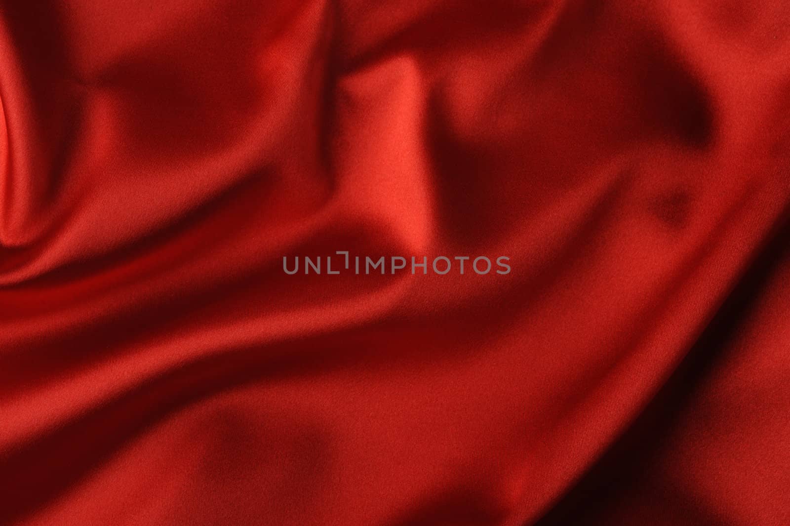 red satin background. A satiny fabric with beautiful light-shadow waves