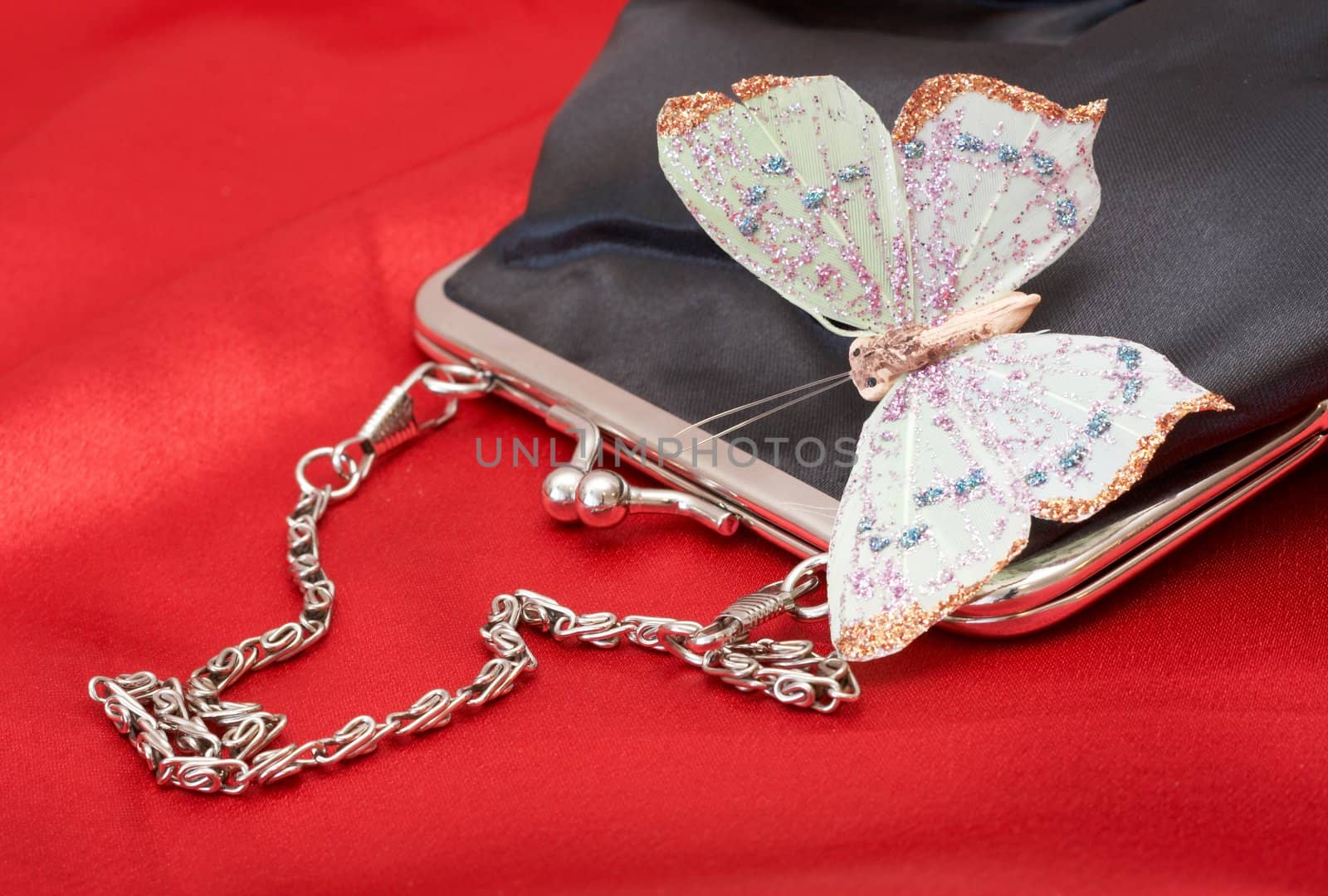 Black purse with colorful butterfly shot on red silk background on Valentines day