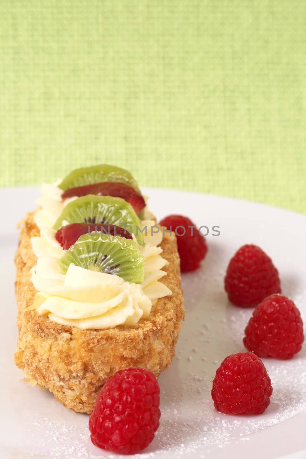 Fruit boat cake with kiwi, strawberries, and raspberries served on a white plate