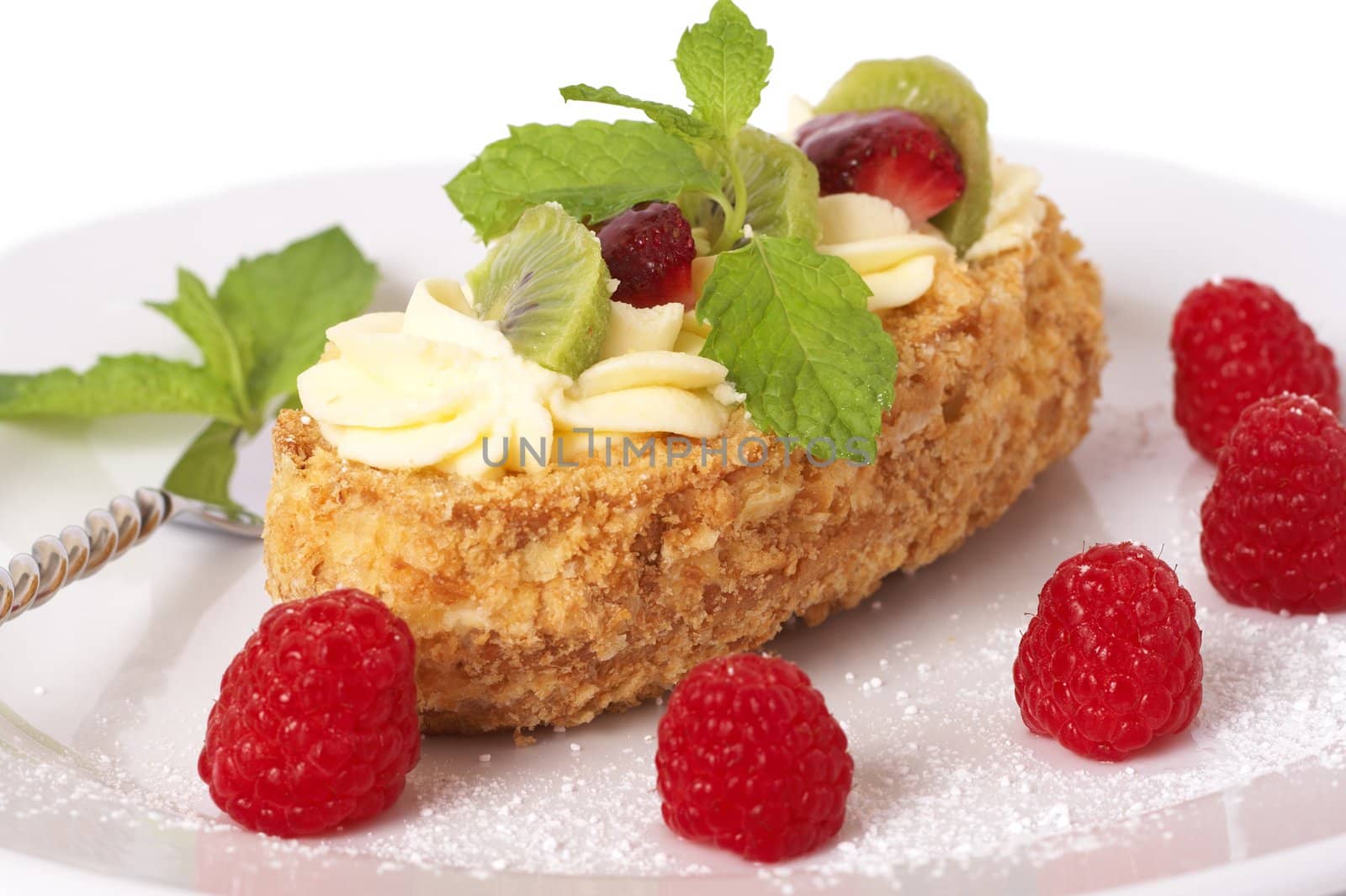 Fruit boat cake with kiwi, strawberries, and raspberries served on a white plate