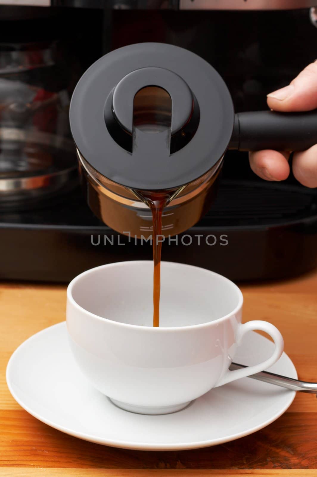 Closeup of coffee being poured into the cup. Shot on light wood background