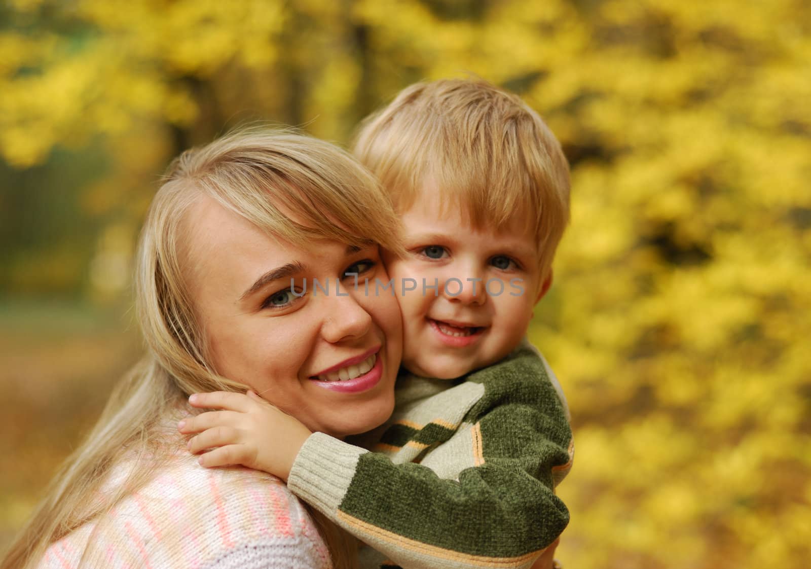 Mother with the child. On a background of yellow autumn foliage