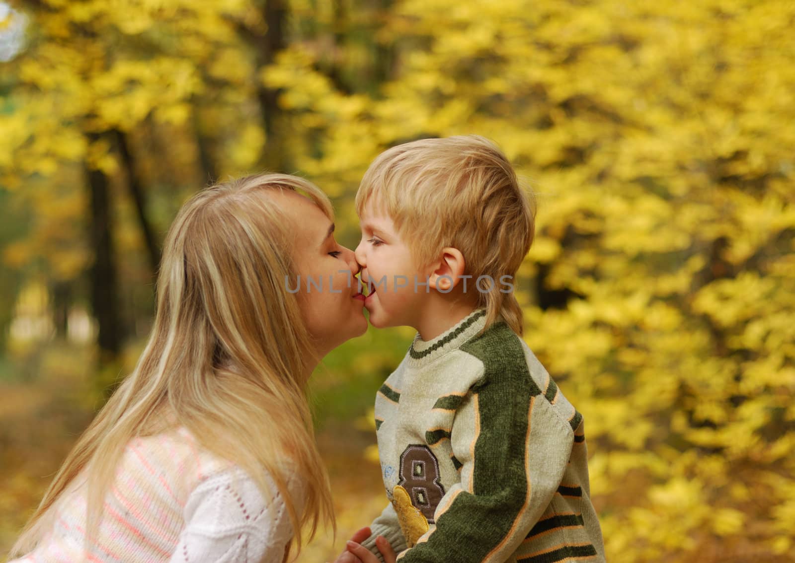 Mother with the child. On a background of yellow autumn foliage