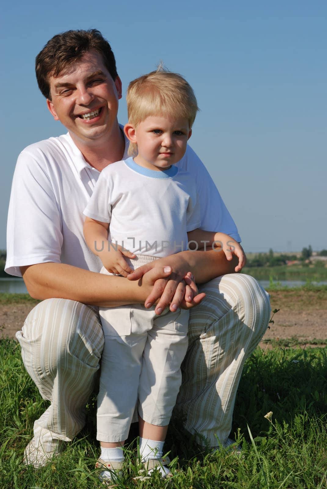 The father and son. Happy people on a meadow with the clear blue sky