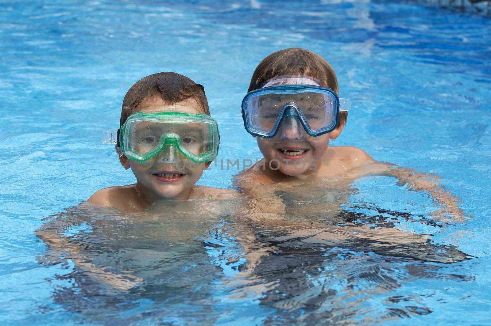 two young boys in pool with goggles on
