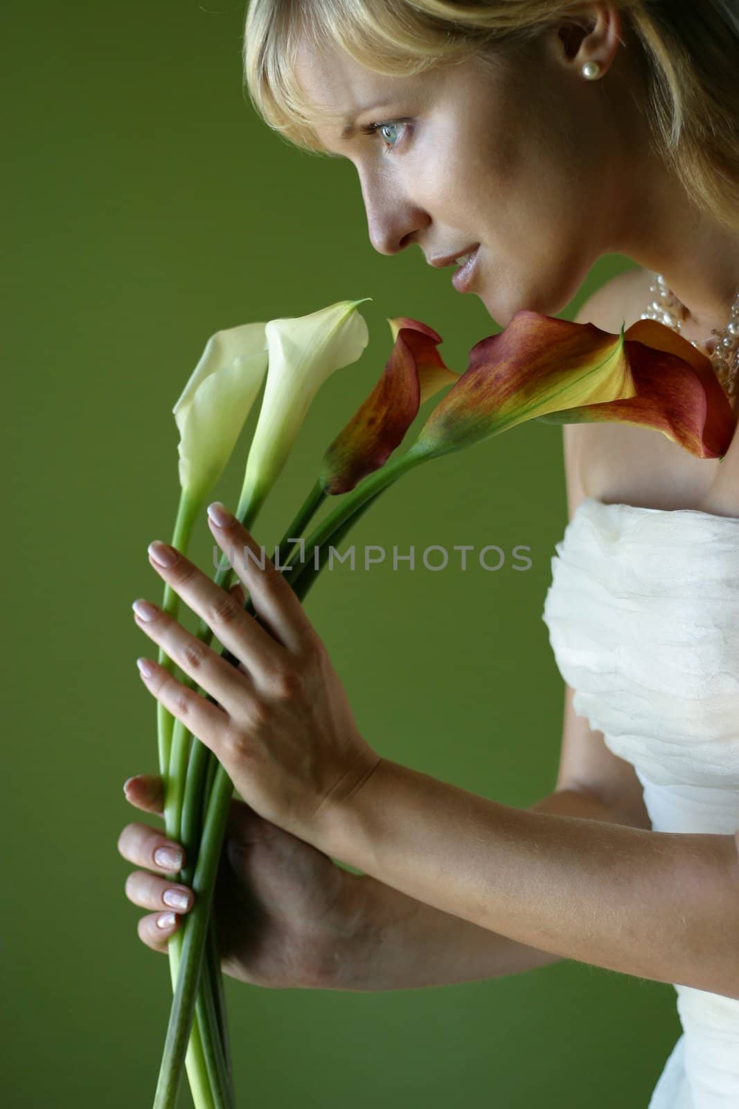 Five callas in hands of the beautiful bride on a green background