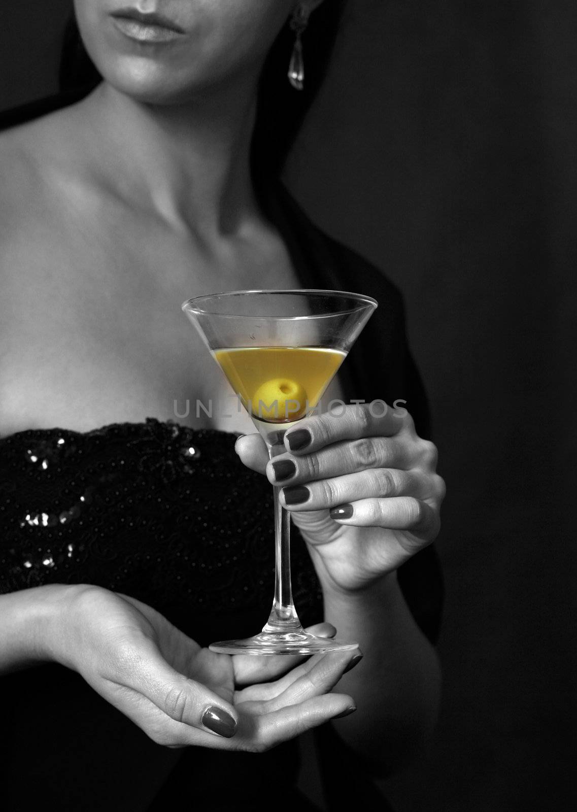 The image of a glass from martinis in a female hand on a black background