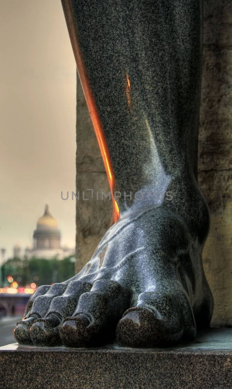 Foot of granite telamon with Saint-Isaac's Cathedral in the background. Saint-Petersburg, Russia.