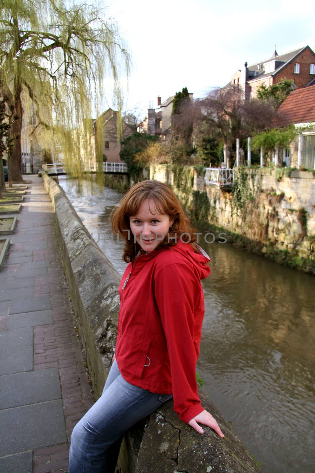 Beautiful young girl sitting on the canal embankment and smiling