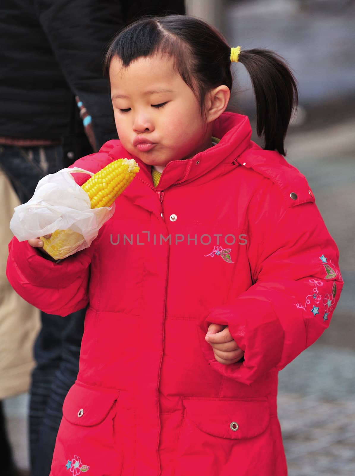 Little Chinese girl eating corn in Shanghai street