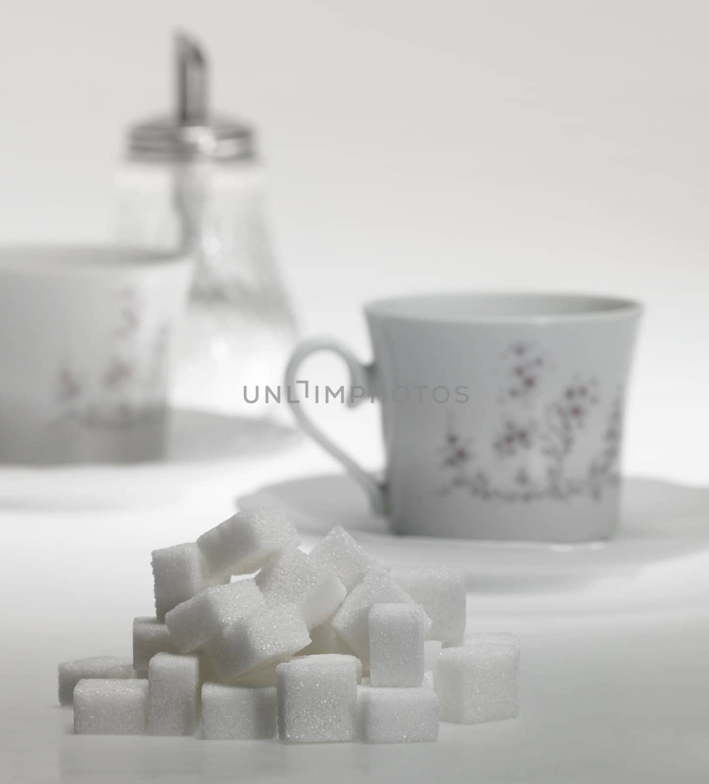 lump sugar pile in front of porcelain ciffee cup in light grey back