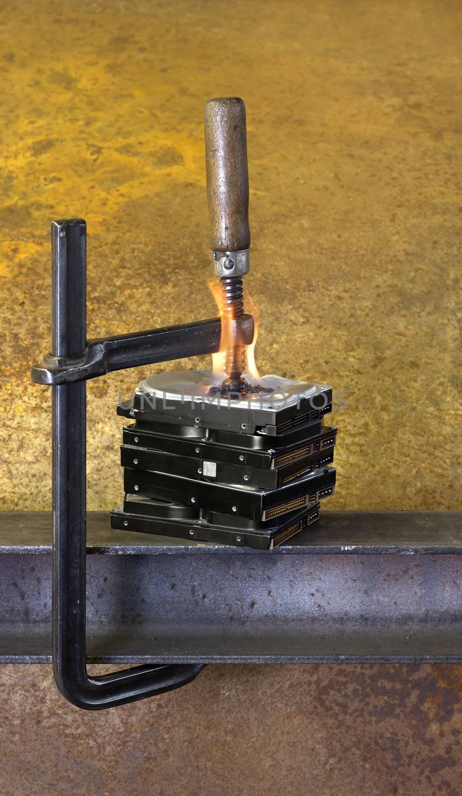 clamp pressing on stack of burning hard drives in rusty background