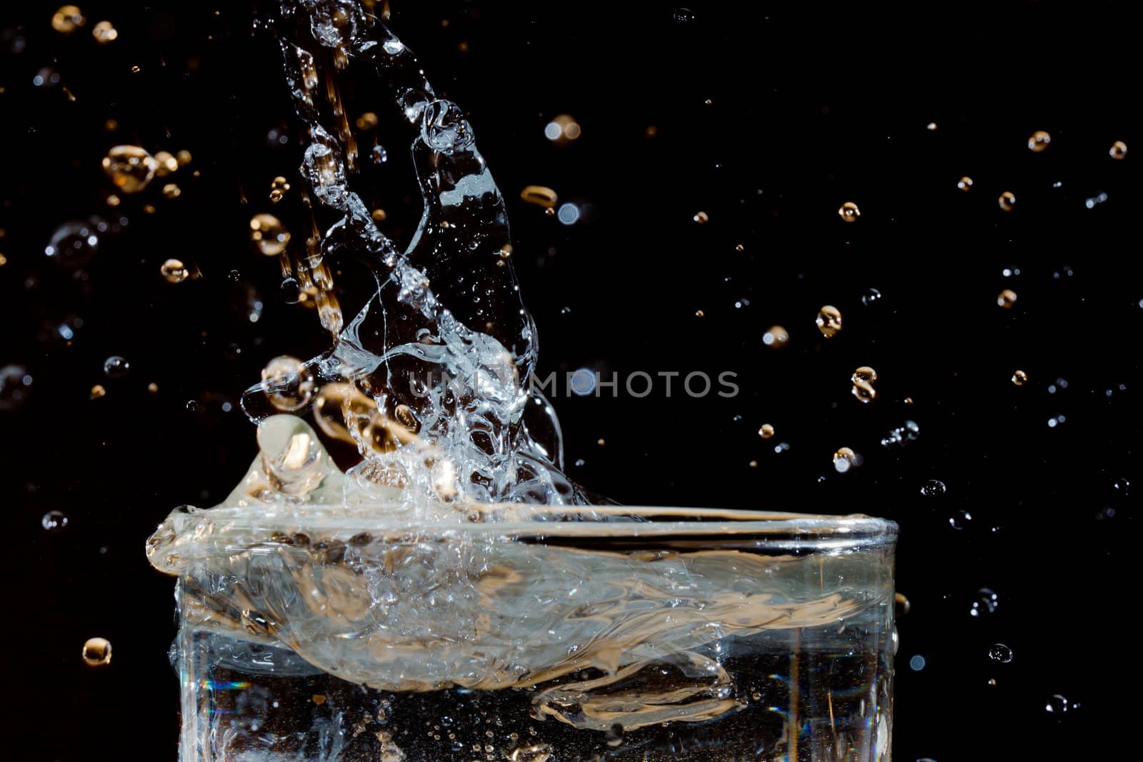 The fluid motion of water being poured into a glass of water forming abstract shapes