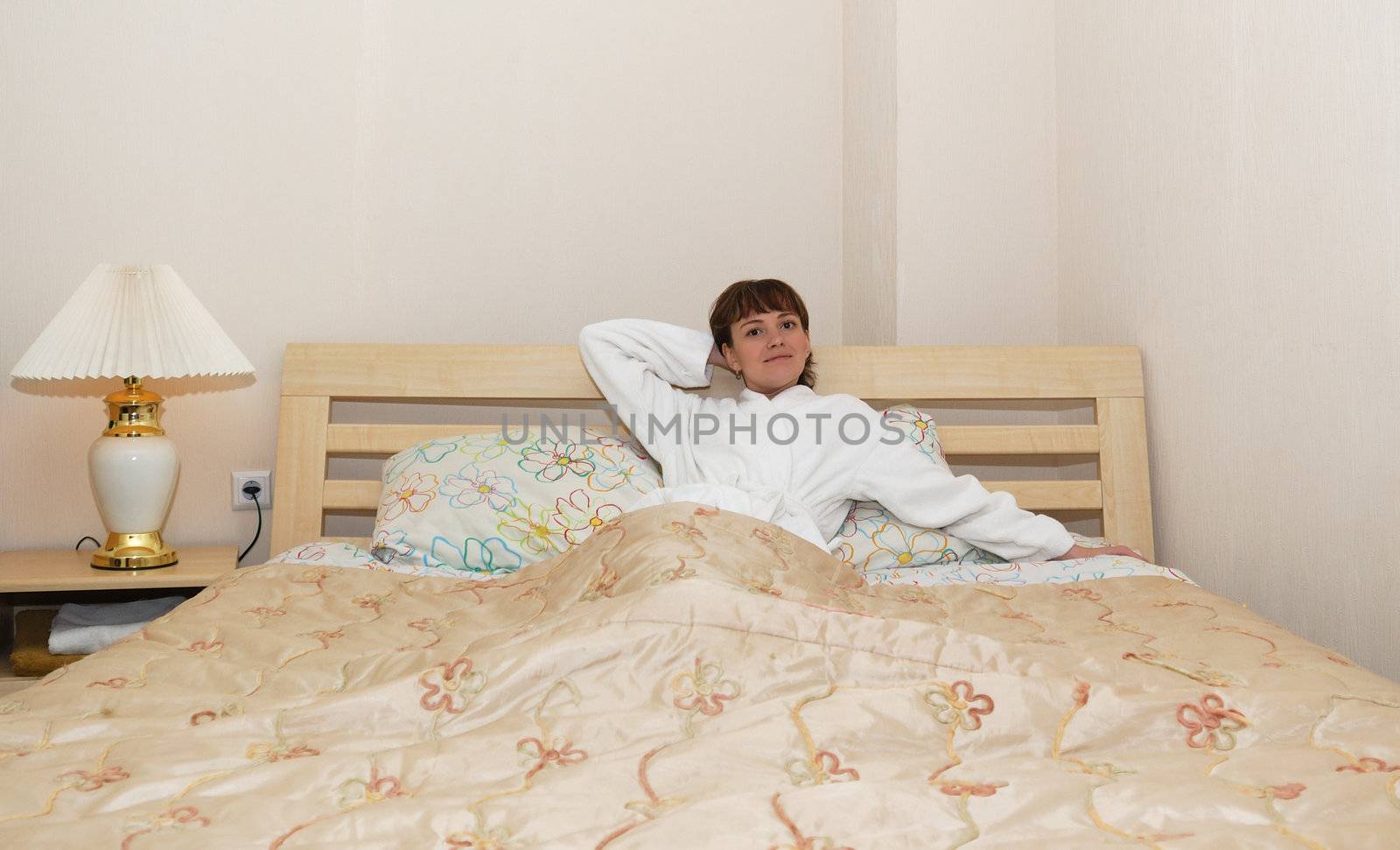 The girl on a bed. It is dressed in a white dressing gown, age of 25 years