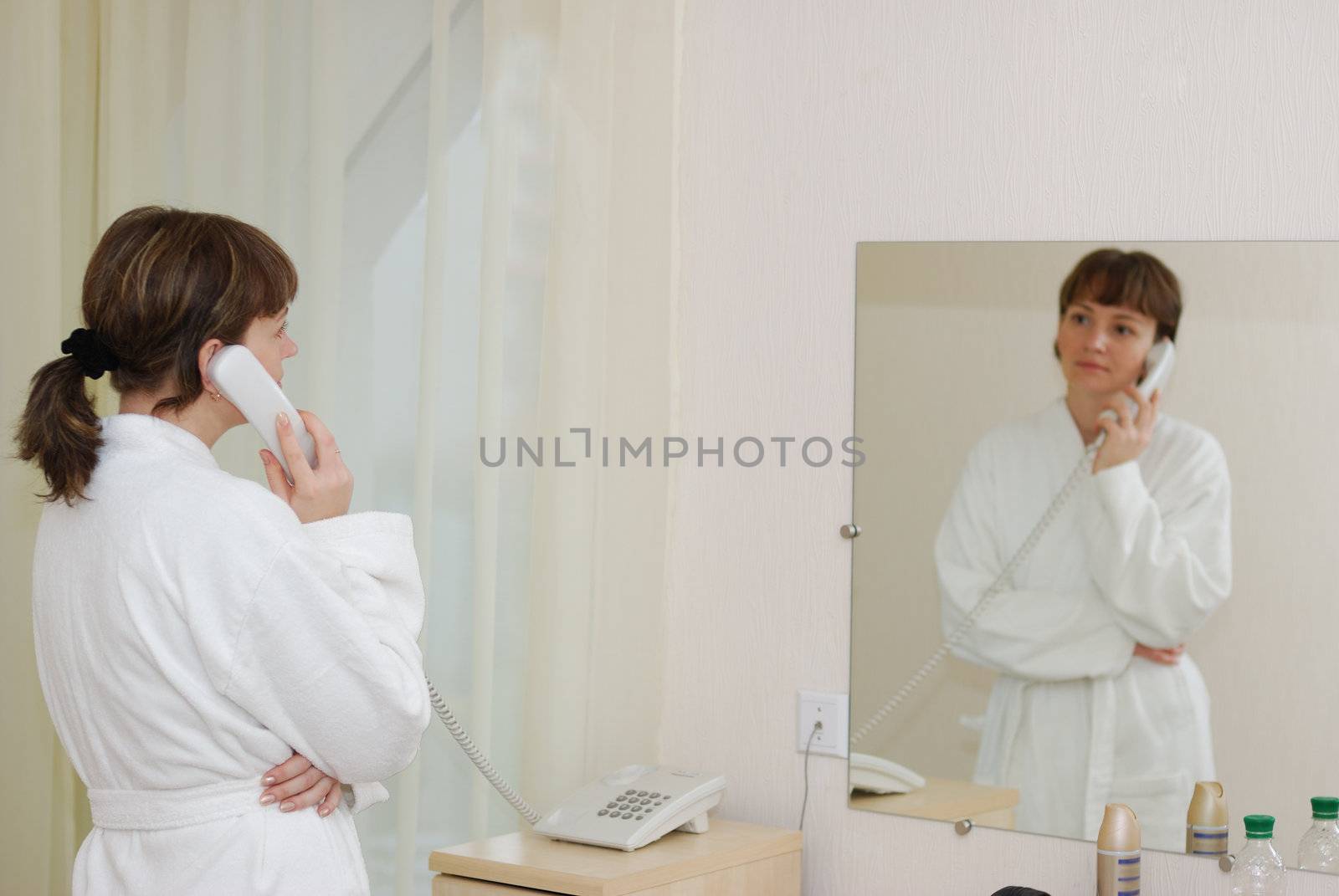 The girl talking by phone. After morning douche in a white dressing gown