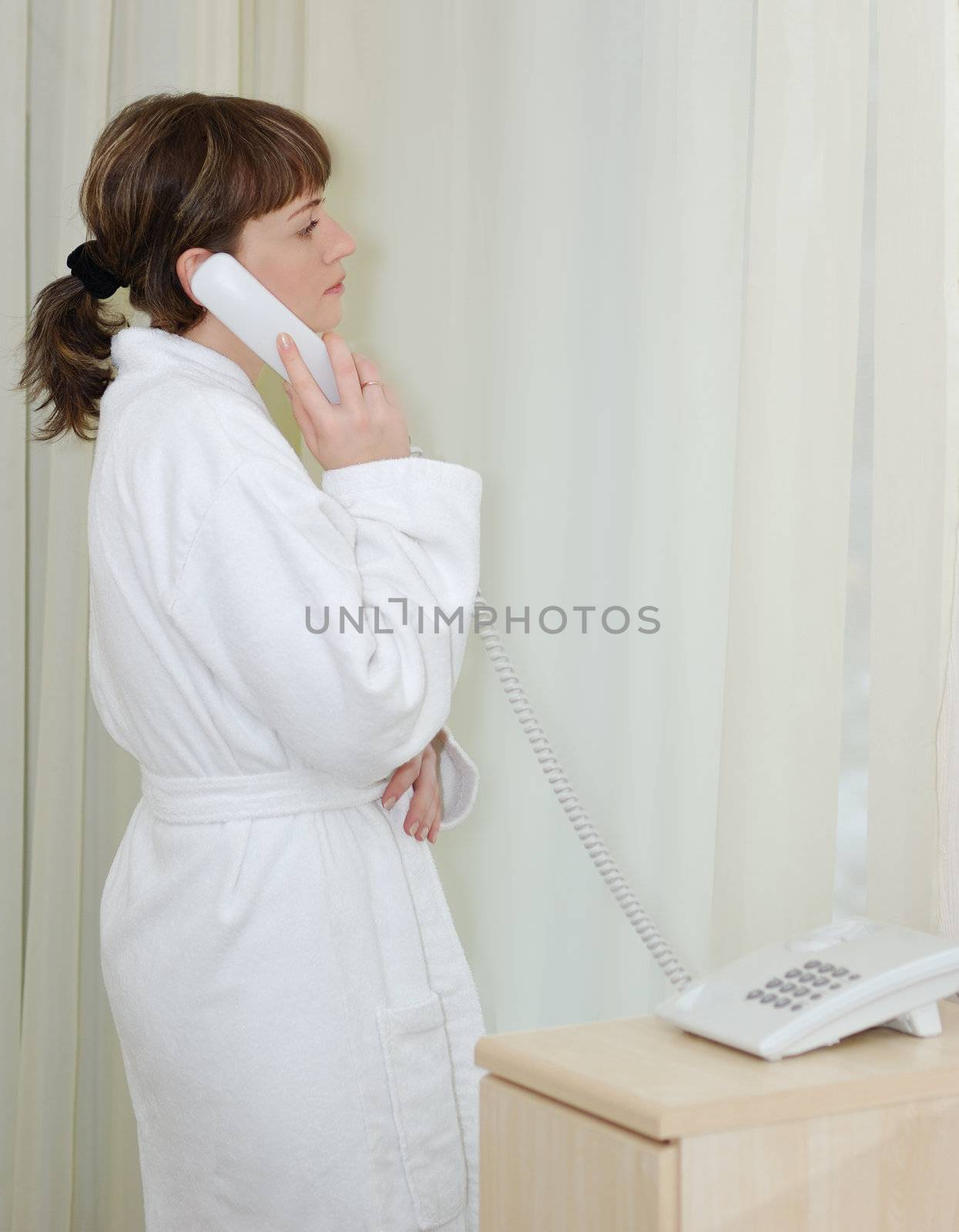 The girl talking by phone. After morning douche in a white dressing gown