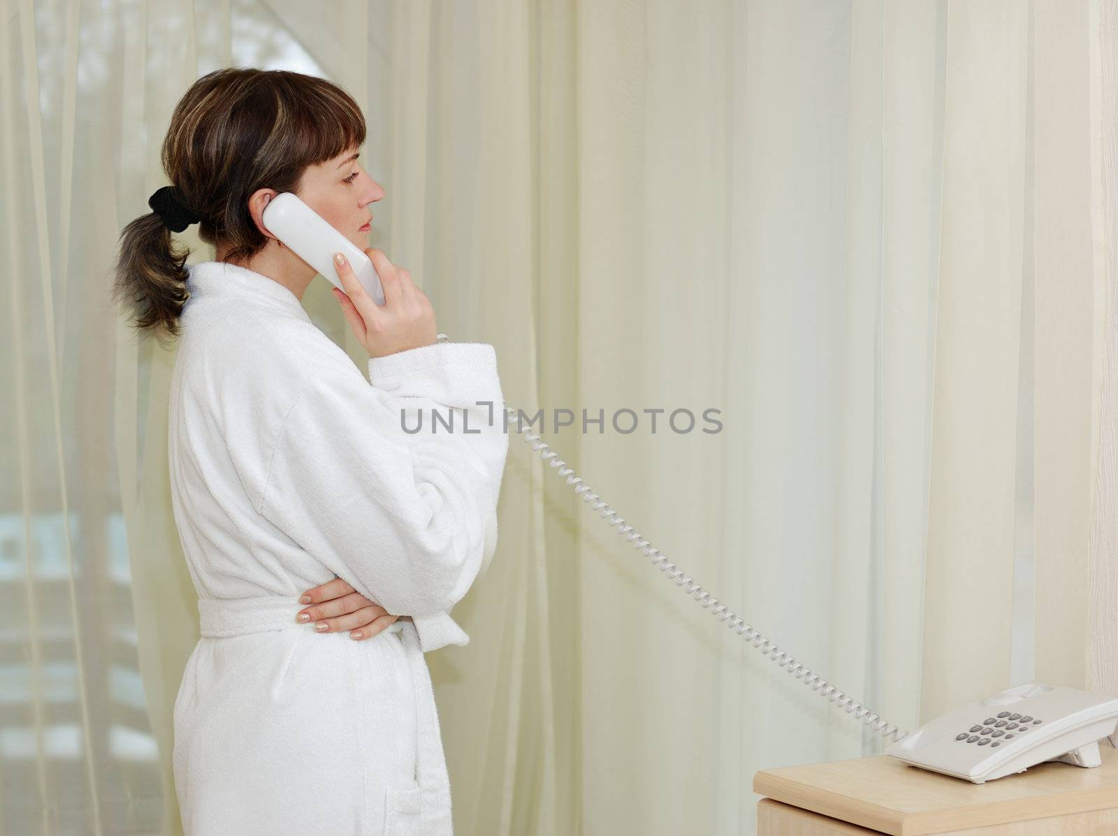The girl talking by phone. After morning douche in a white dressing gown