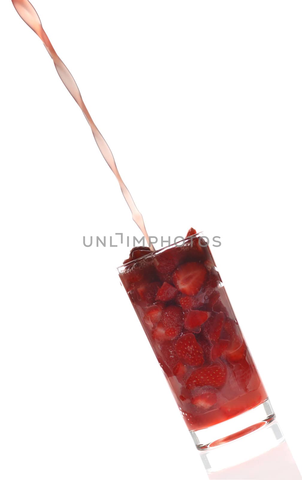 Strawberry juice. A fresh fruit juice flowing in a glass. In a glass the cut fruit