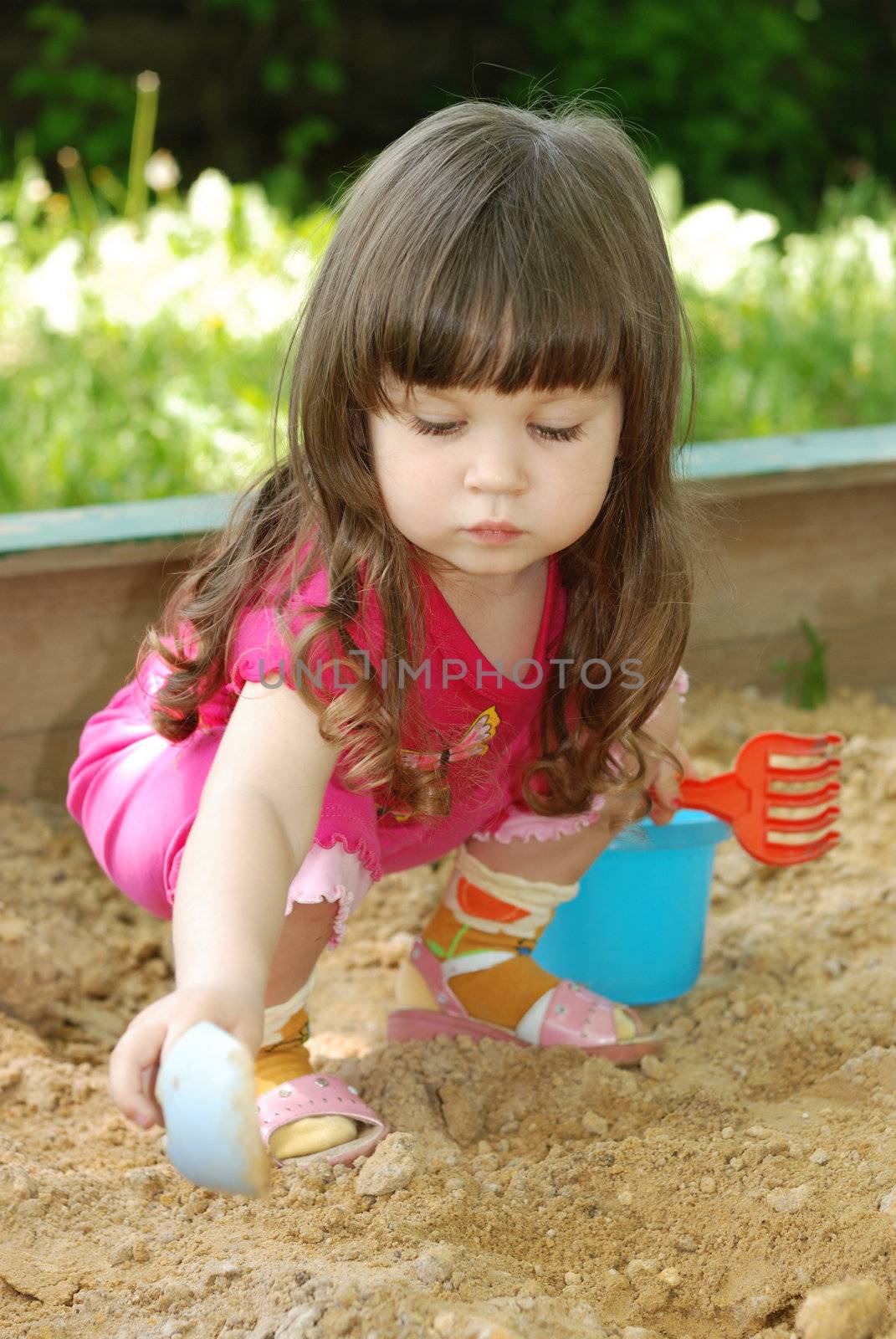 The girl playing to a sandbox. Caucasian the child, park of rest