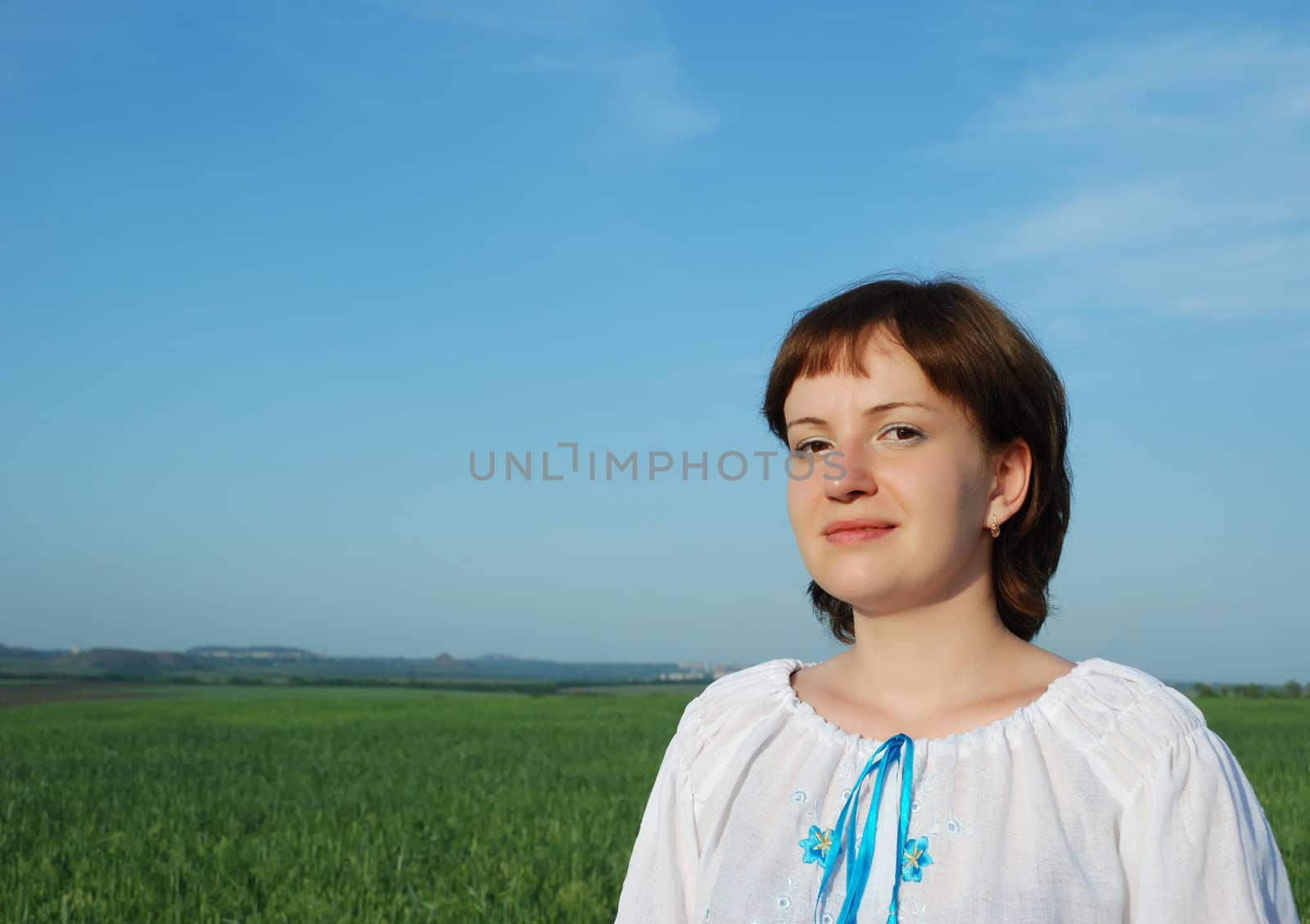 The Russian woman in national clothes. On a background of the sky and a field