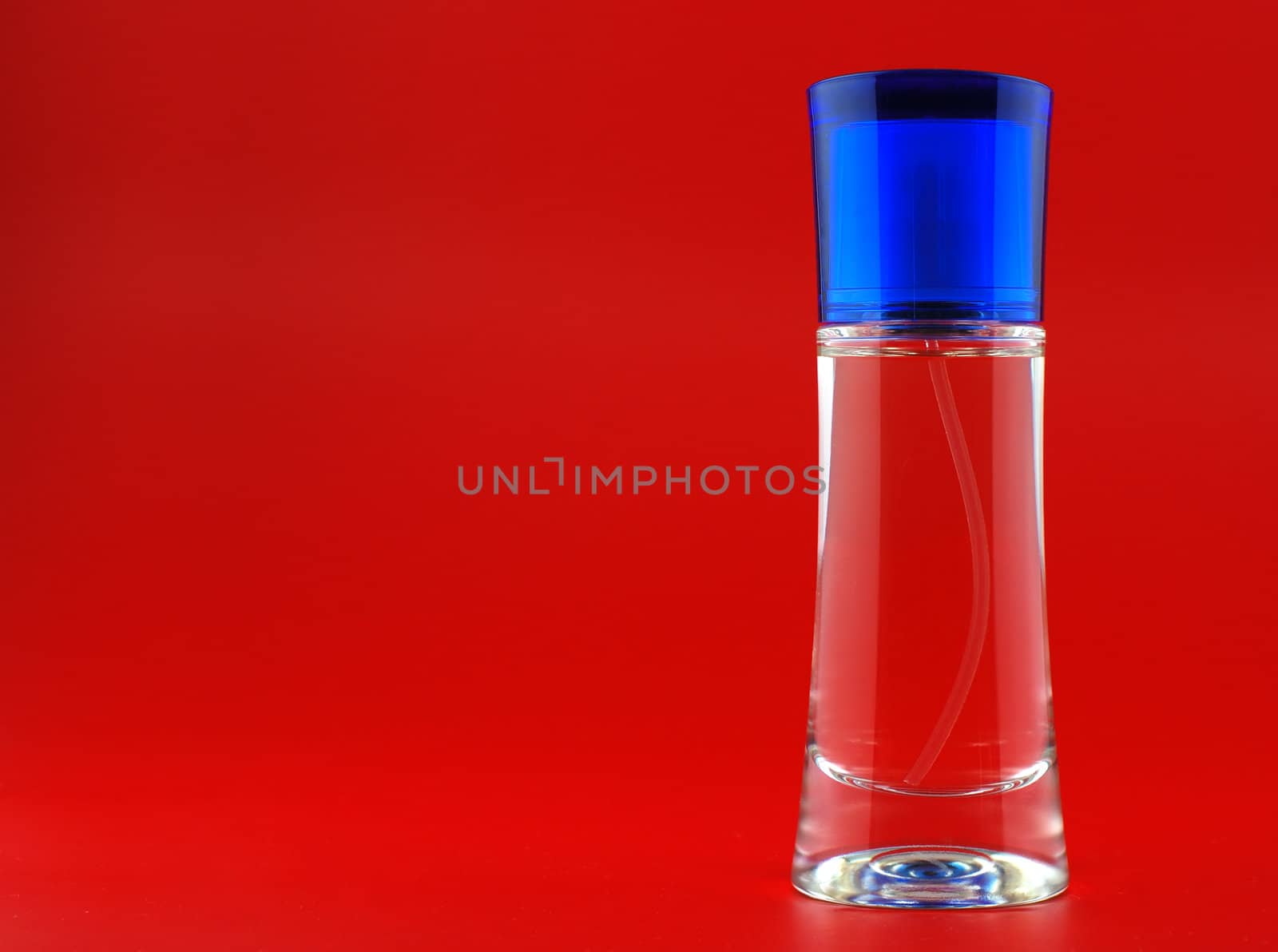 perfume. A bottle perfume on a red background with effective illumination