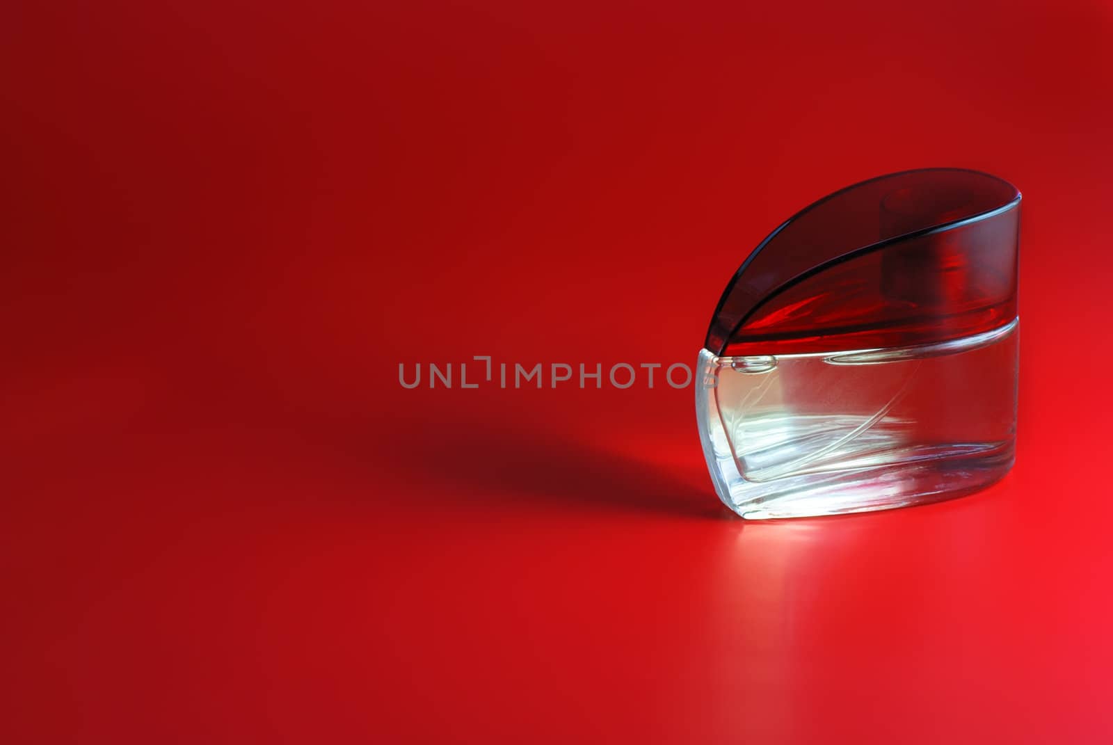 perfume. A bottle perfume on a red background with effective illumination